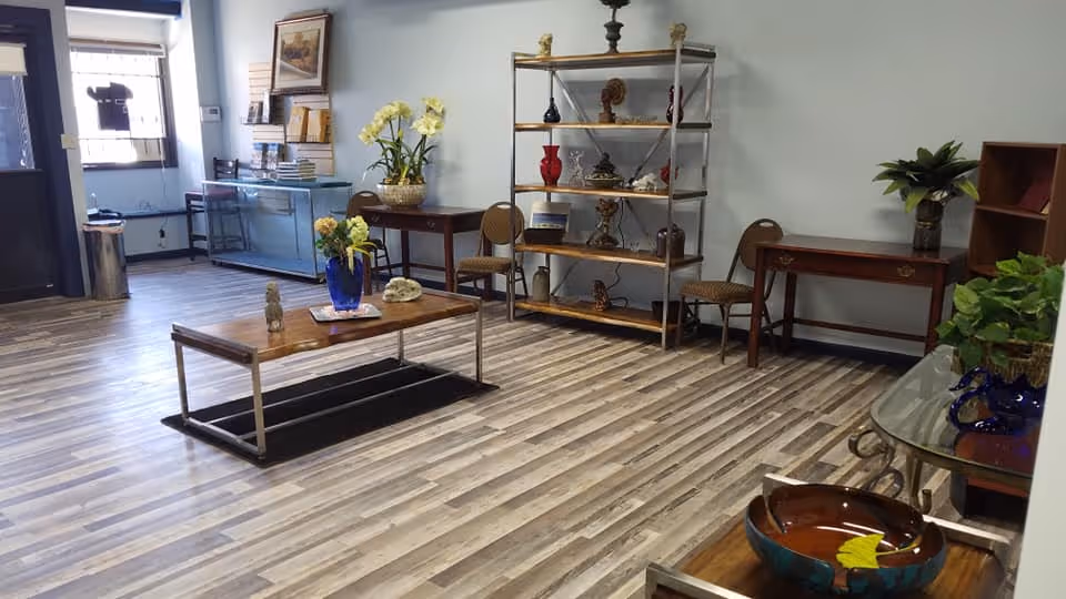 Interior lounge area with shelves, tables, and plants in a senior living facility.