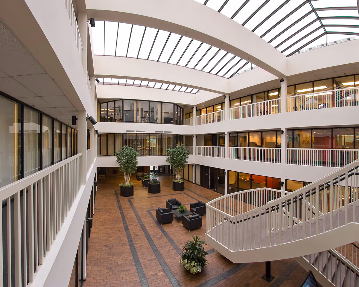 Inside atrium of a senior living center with glass skylight, balconies, and seating.