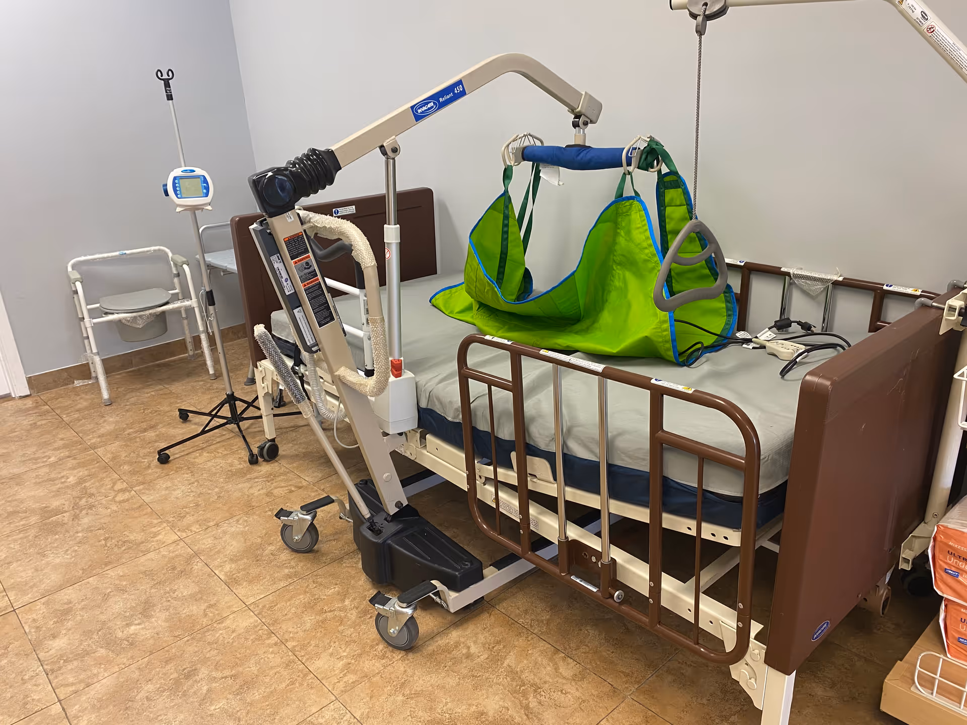 Senior living facility room with a bed, patient lift, and mobility devices.