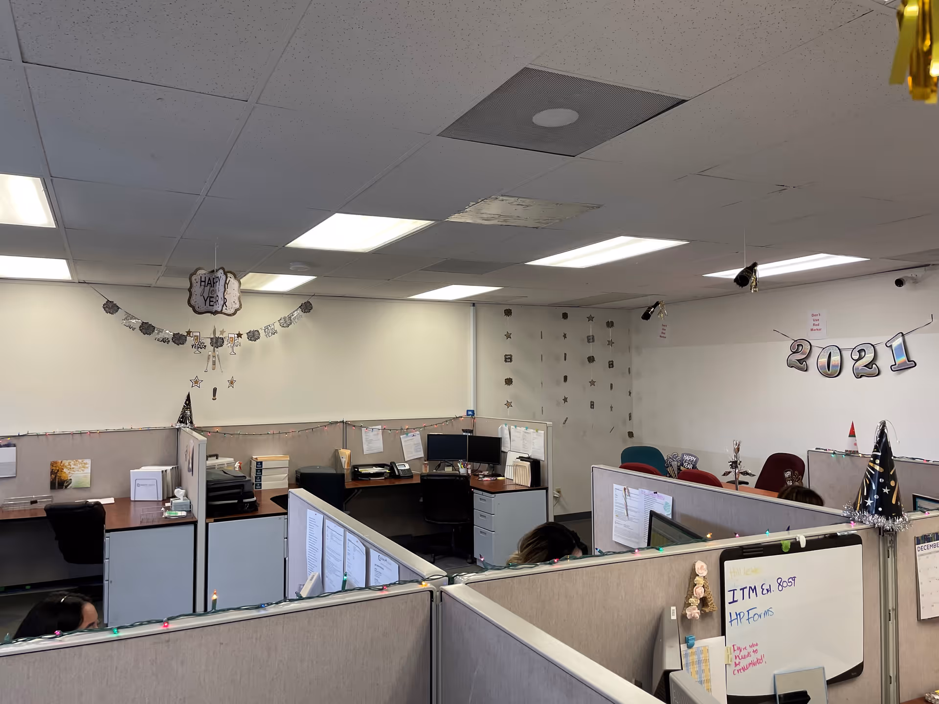 Open-plan office with cubicles, desks, computers, and holiday decorations.