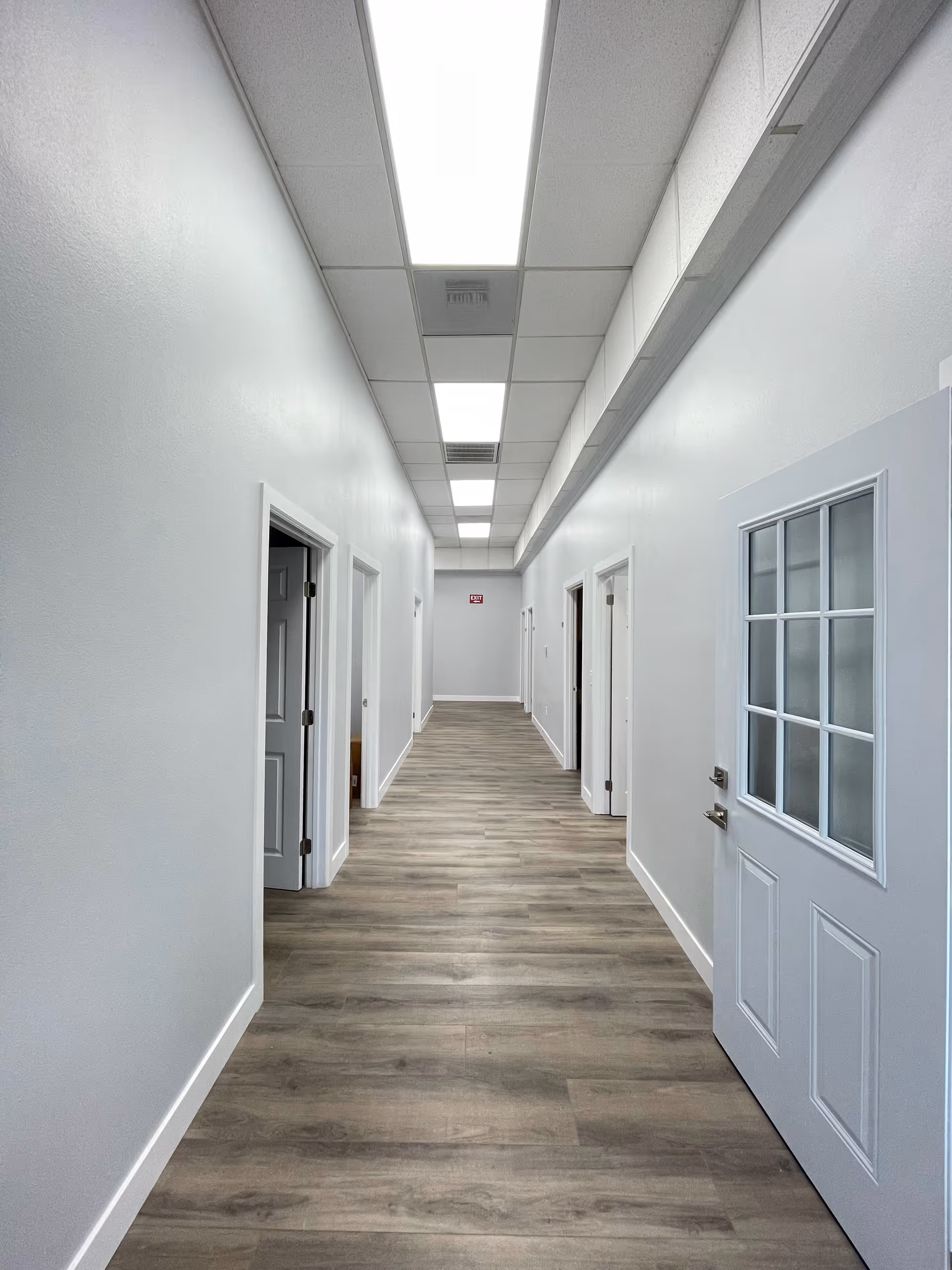 Bright interior hallway in a senior living facility with doors along both walls.