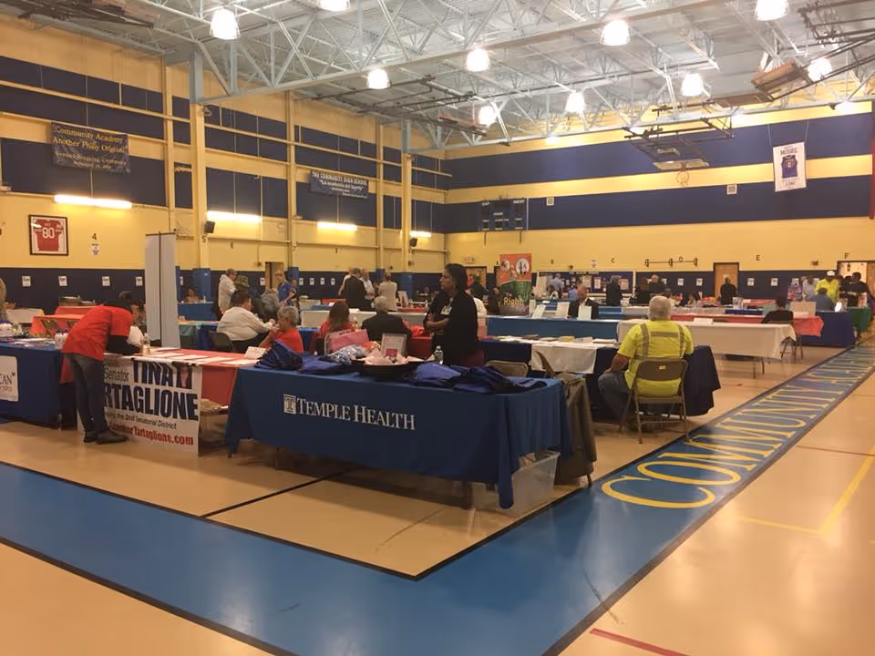 Indoor gym with several booths and people at a community health fair.