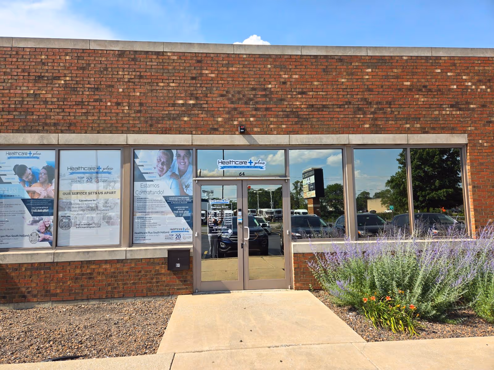 Exterior of Healthcare Plus Caregivers building with glass entrance doors and blooming shrubs