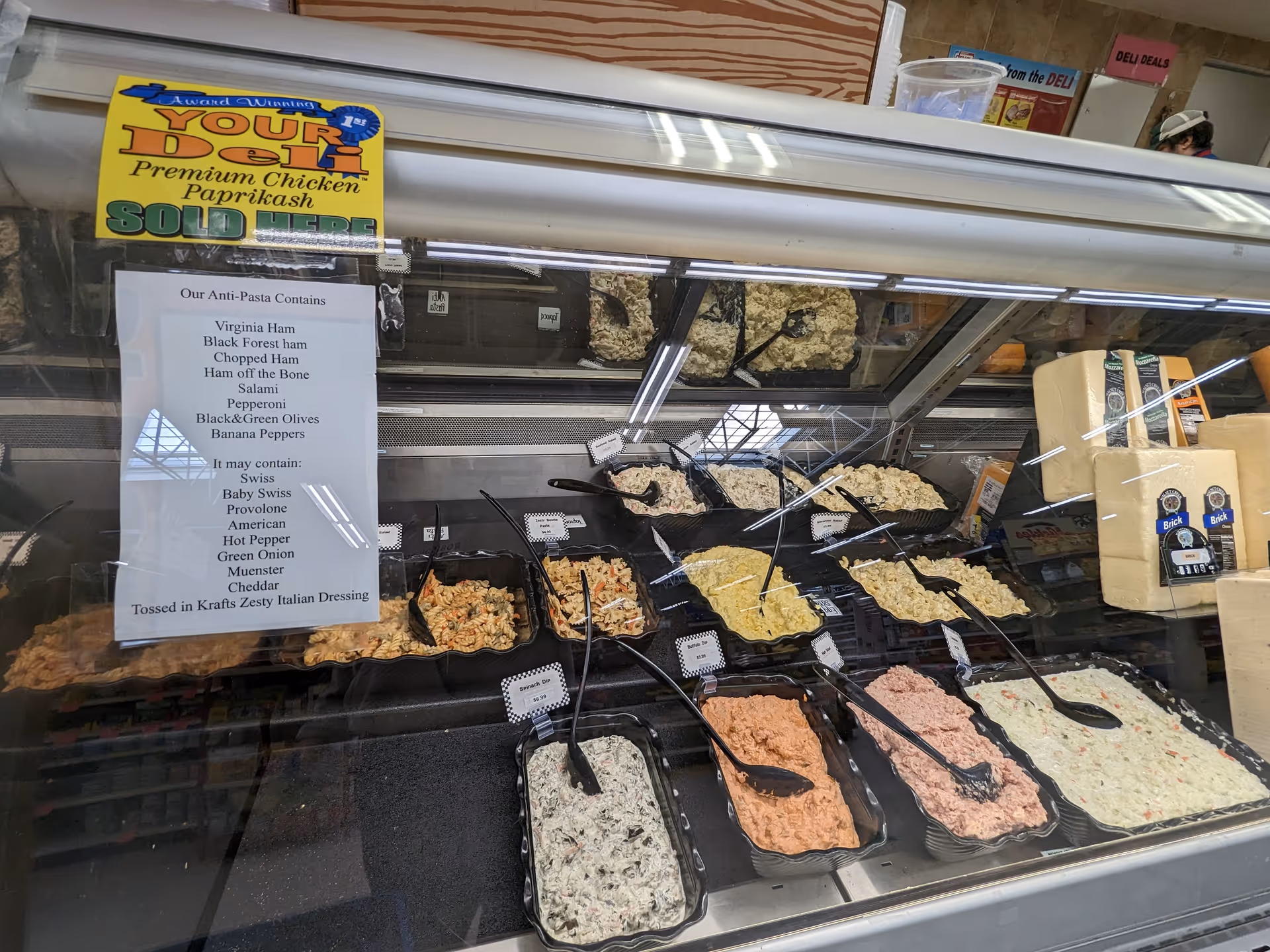Deli counter at Discount Drug Mart with assorted salads and cheeses behind glass.