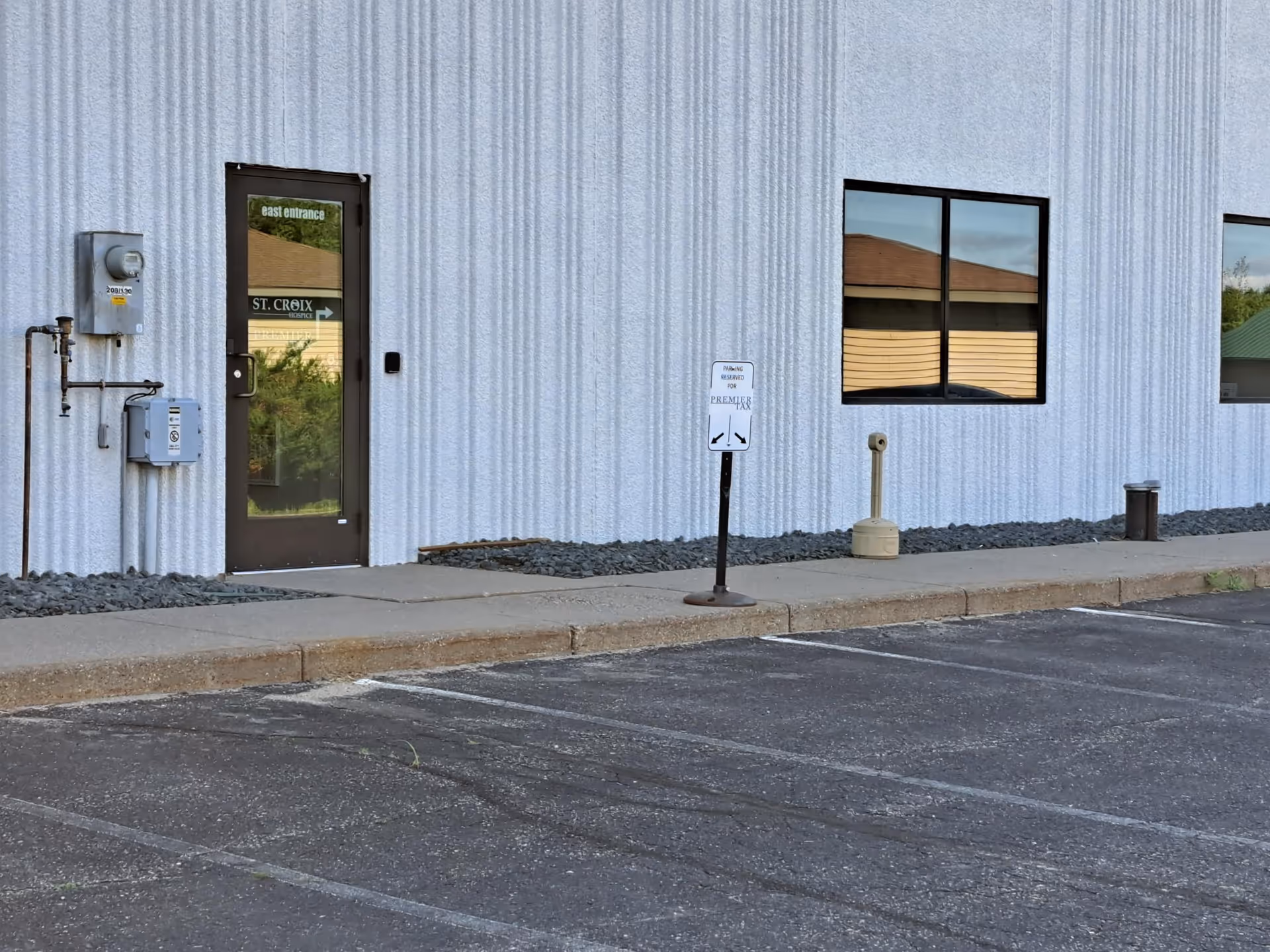 Exterior wall of St. Croix Hospice building with door, windows, parking, and a handicap sign.