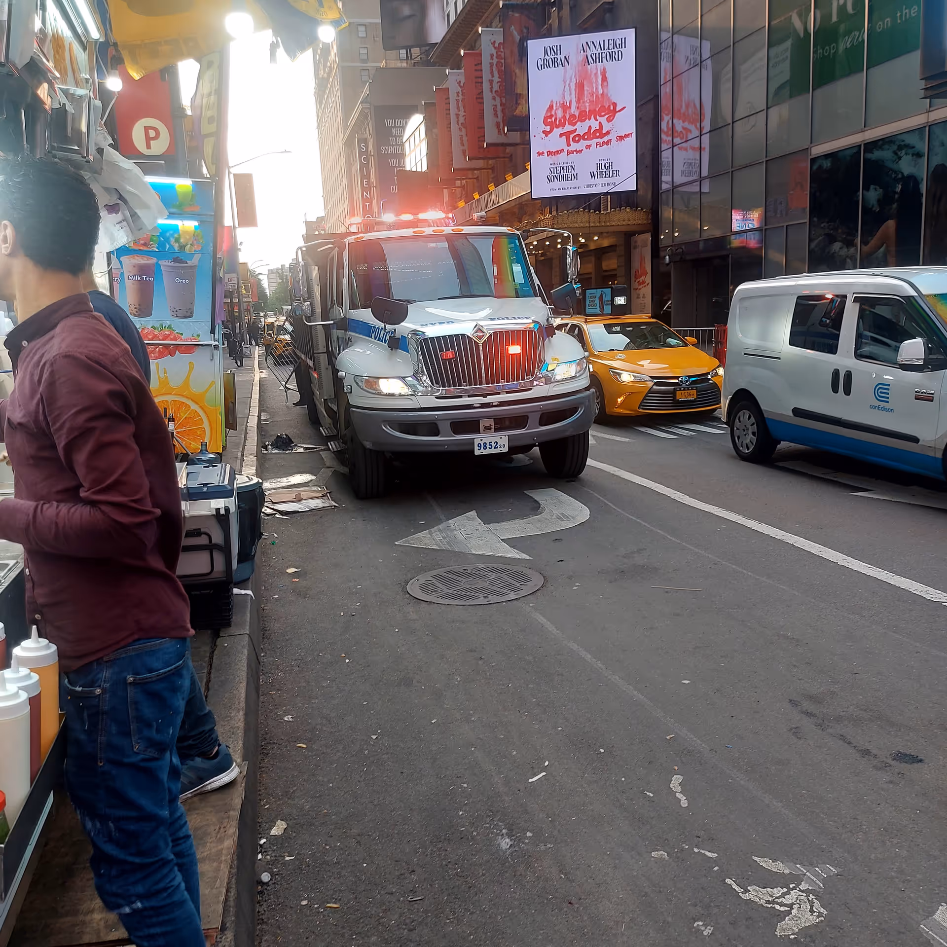 Busy city street with an emergency vehicle, taxis, storefronts, and pedestrians.
