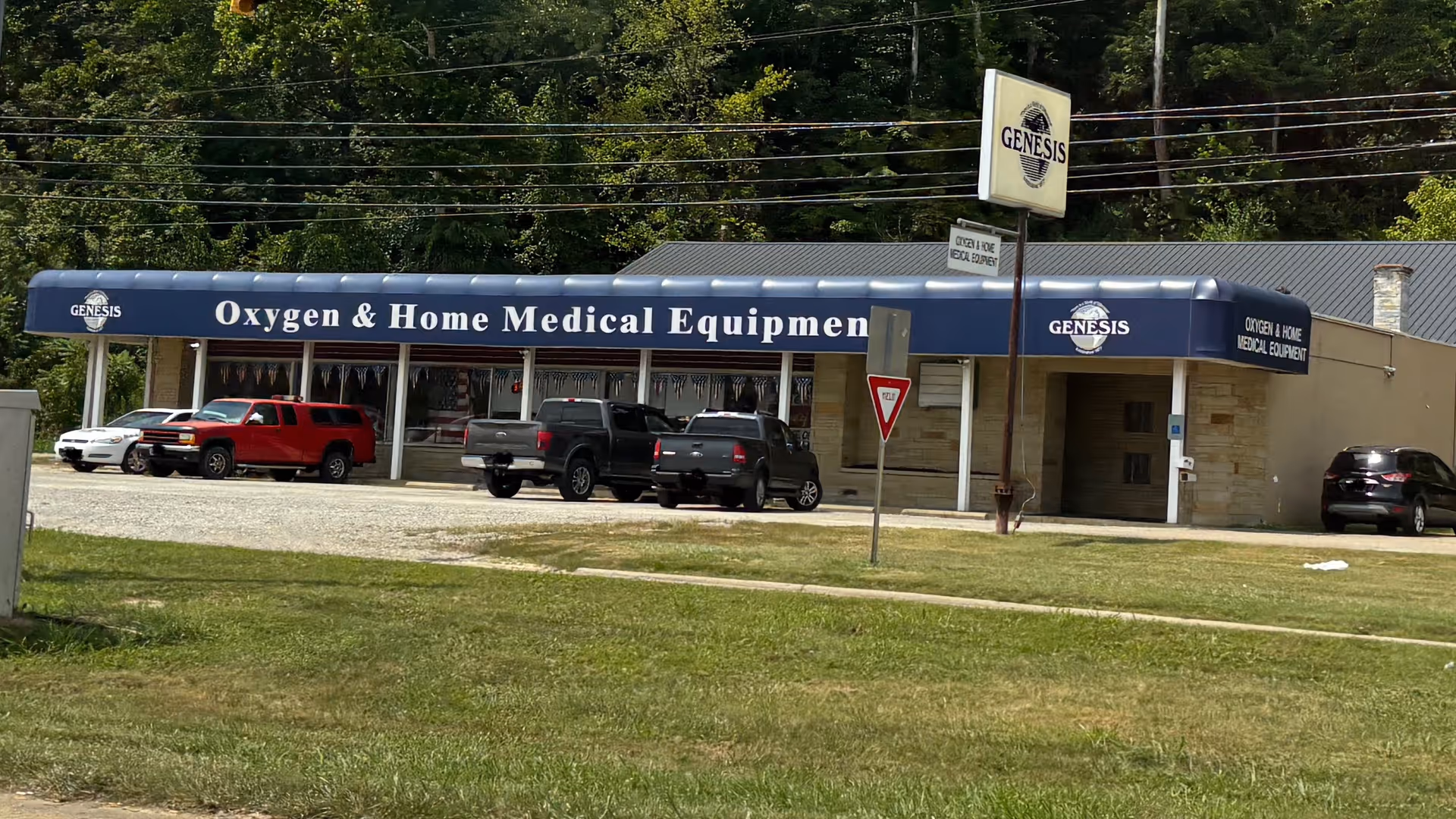 Front view of Genesis Oxygen & Home Medical Equipment storefront with several parked cars.