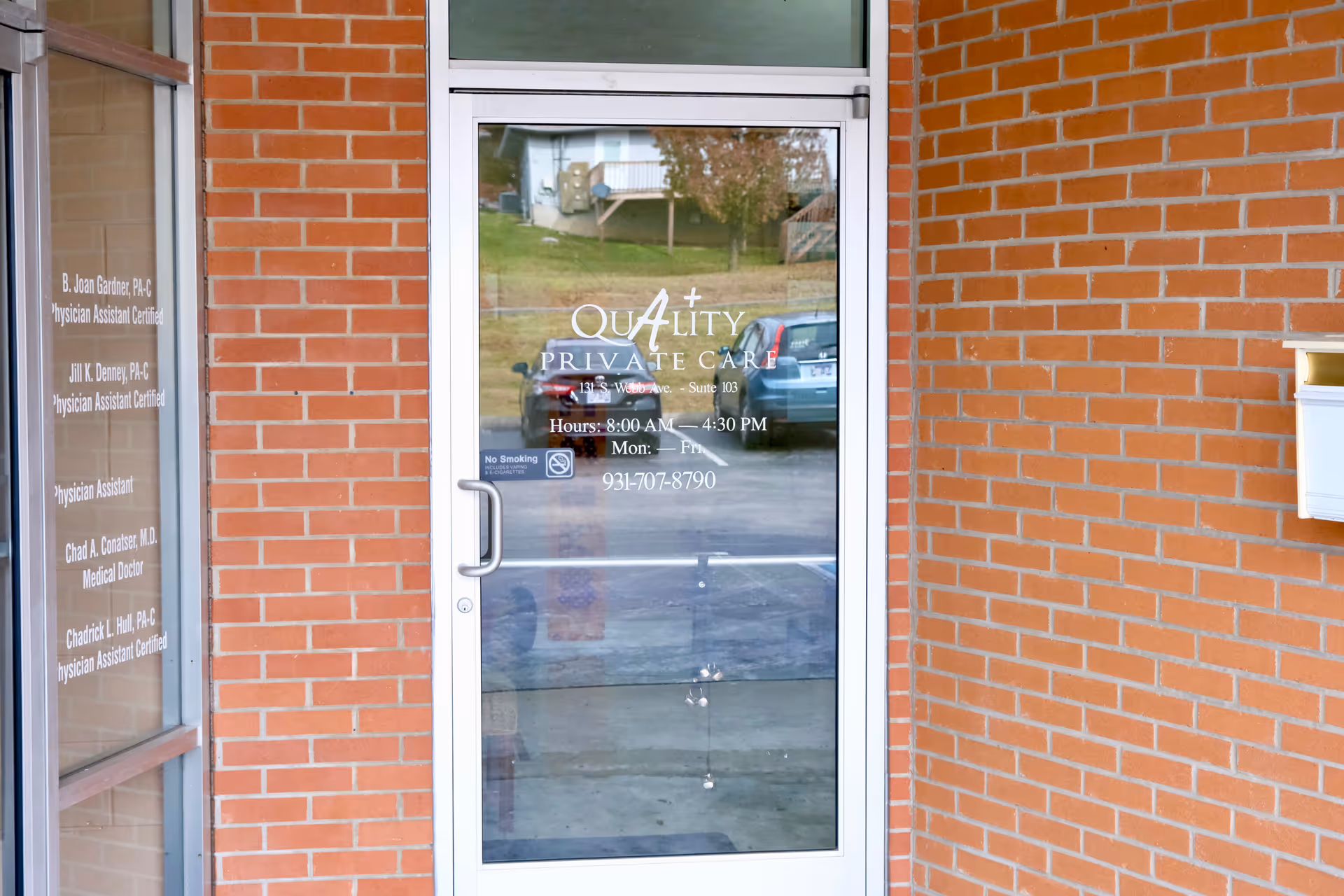 Glass door entrance with Quality Private Care sign on a brick building exterior.