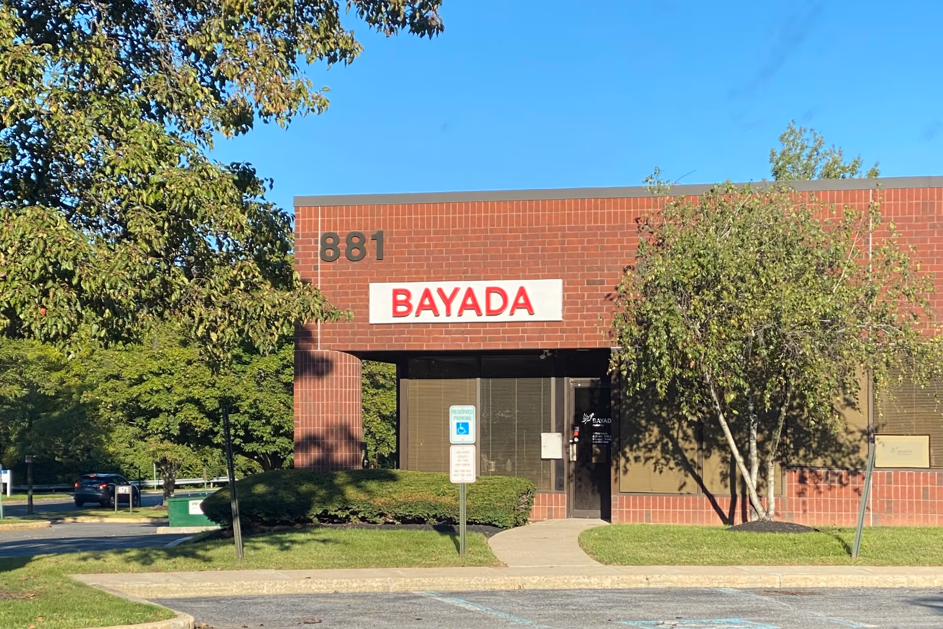 Brick BAYADA Pediatrics building front with sign and trees.