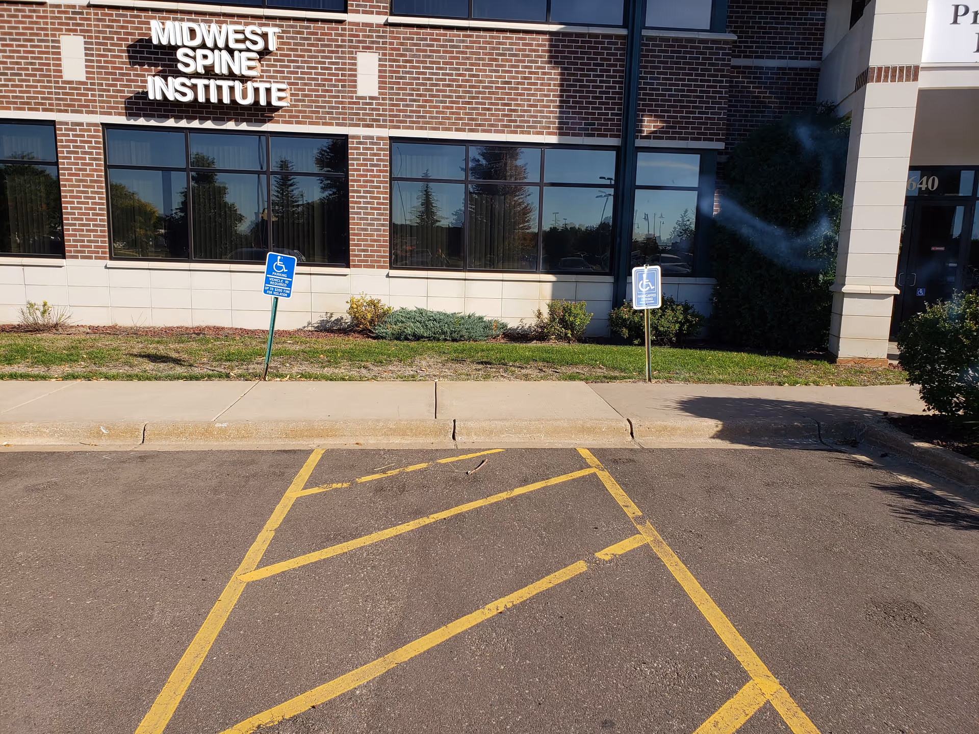 Brick building facade with Midwest Spine Institute sign and handicap parking signs in front.