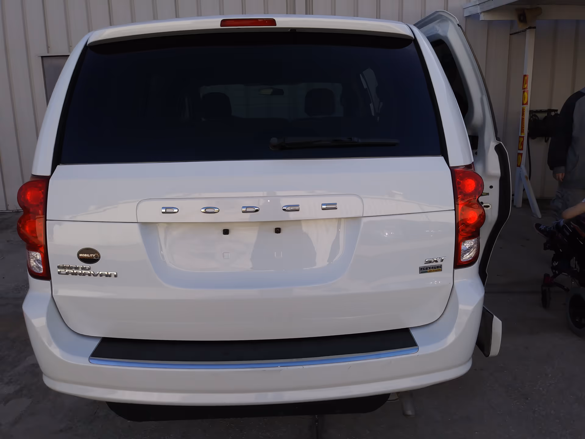 Rear view of a white MobilityWorks van with the side door open outdoors.