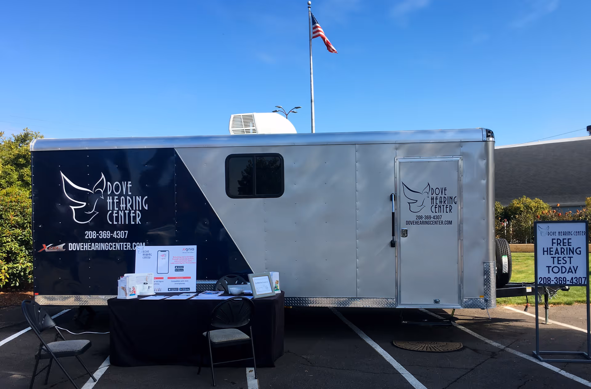 Dove Hearing Center trailer parked outdoors with information table and signage