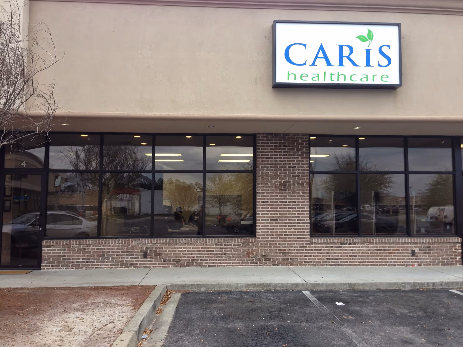 Exterior view of Caris Healthcare building with brick facade and large storefront windows.