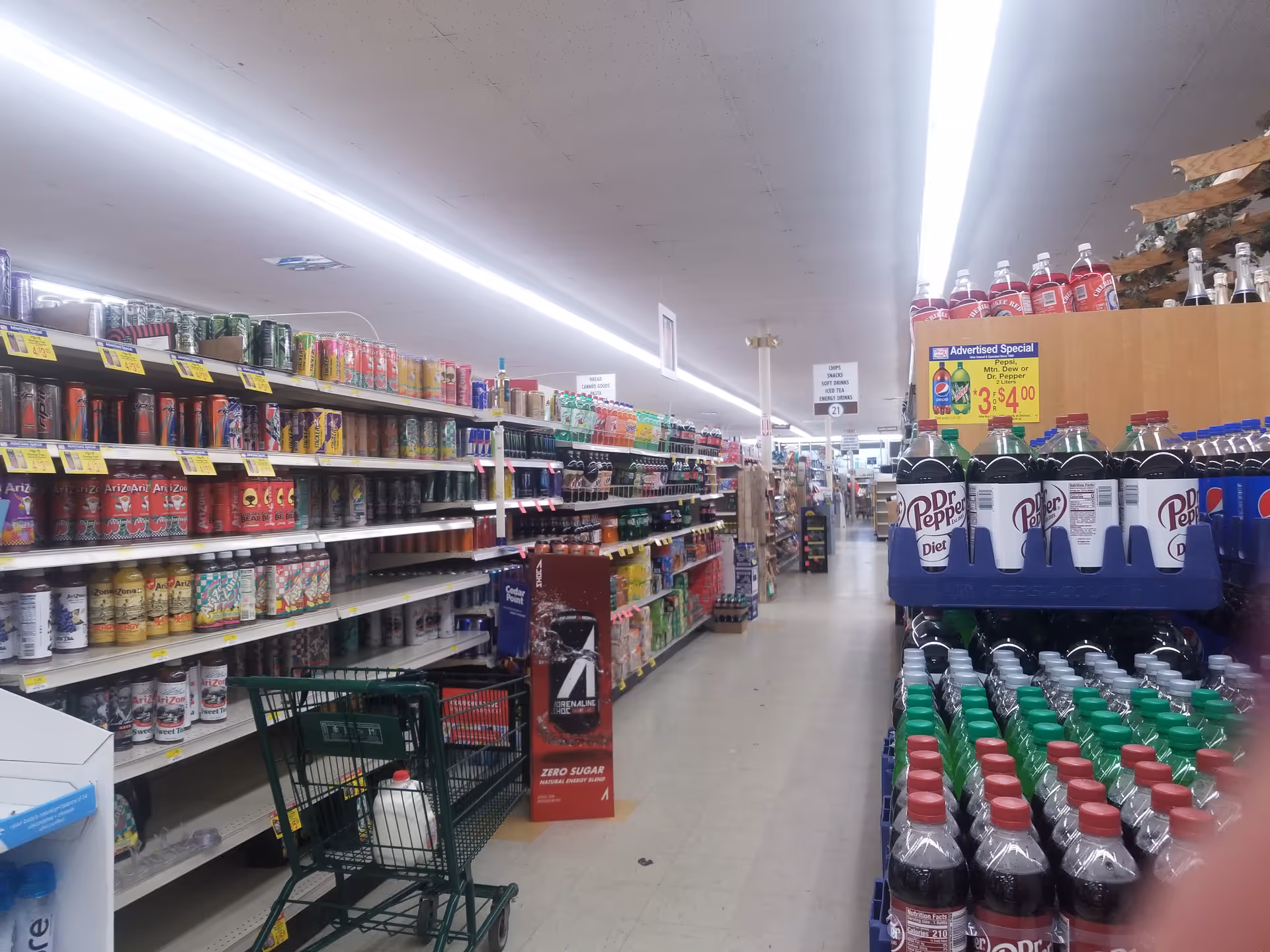 Interior aisle at Discount Drug Mart with shelves of beverages and soda bottles.