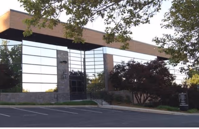 Front view of an Amada Senior Care building with glass facade and parking lot.