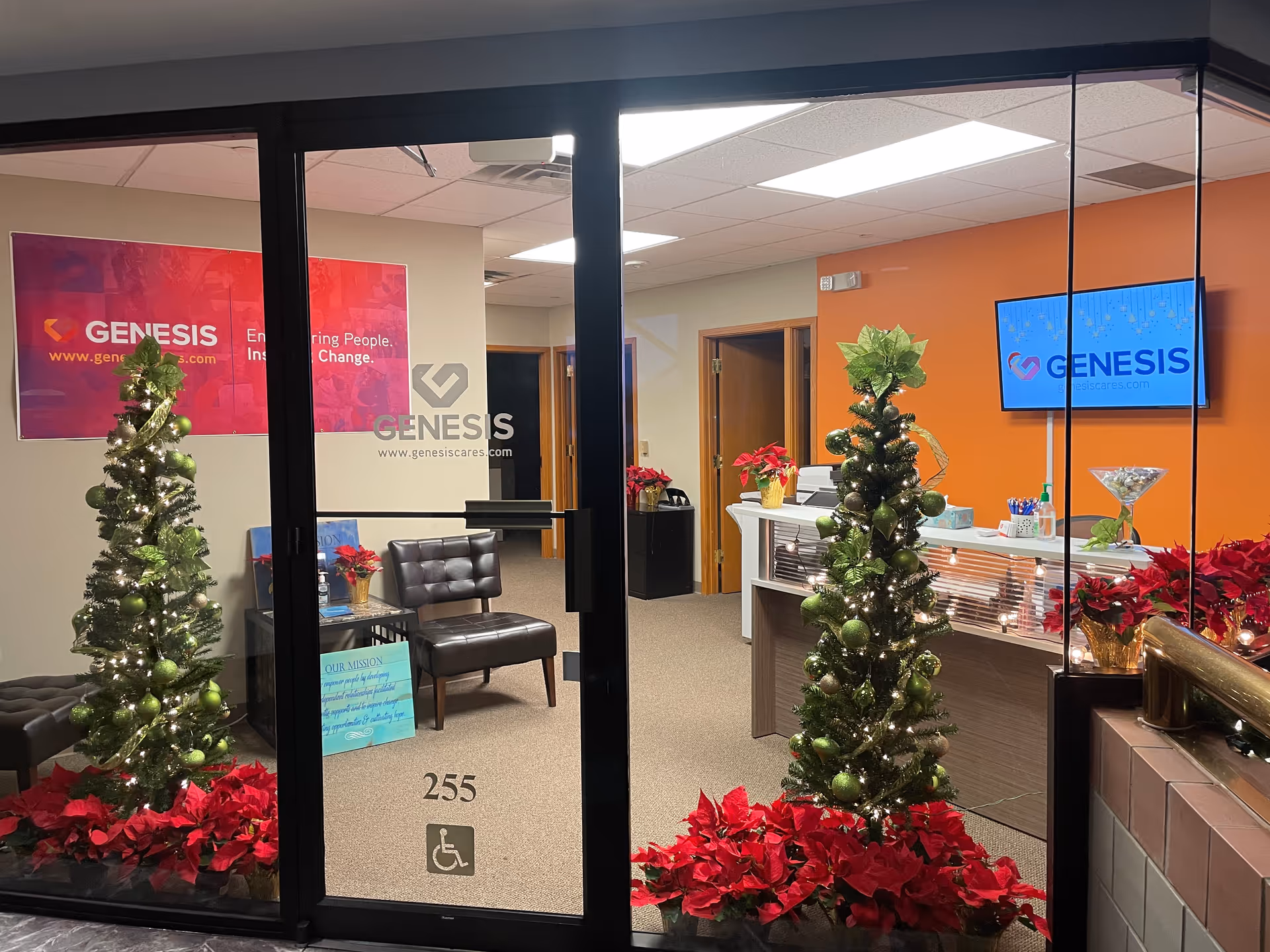 Interior lobby of Genesis In Home Care with Christmas trees, poinsettias, and a reception desk.