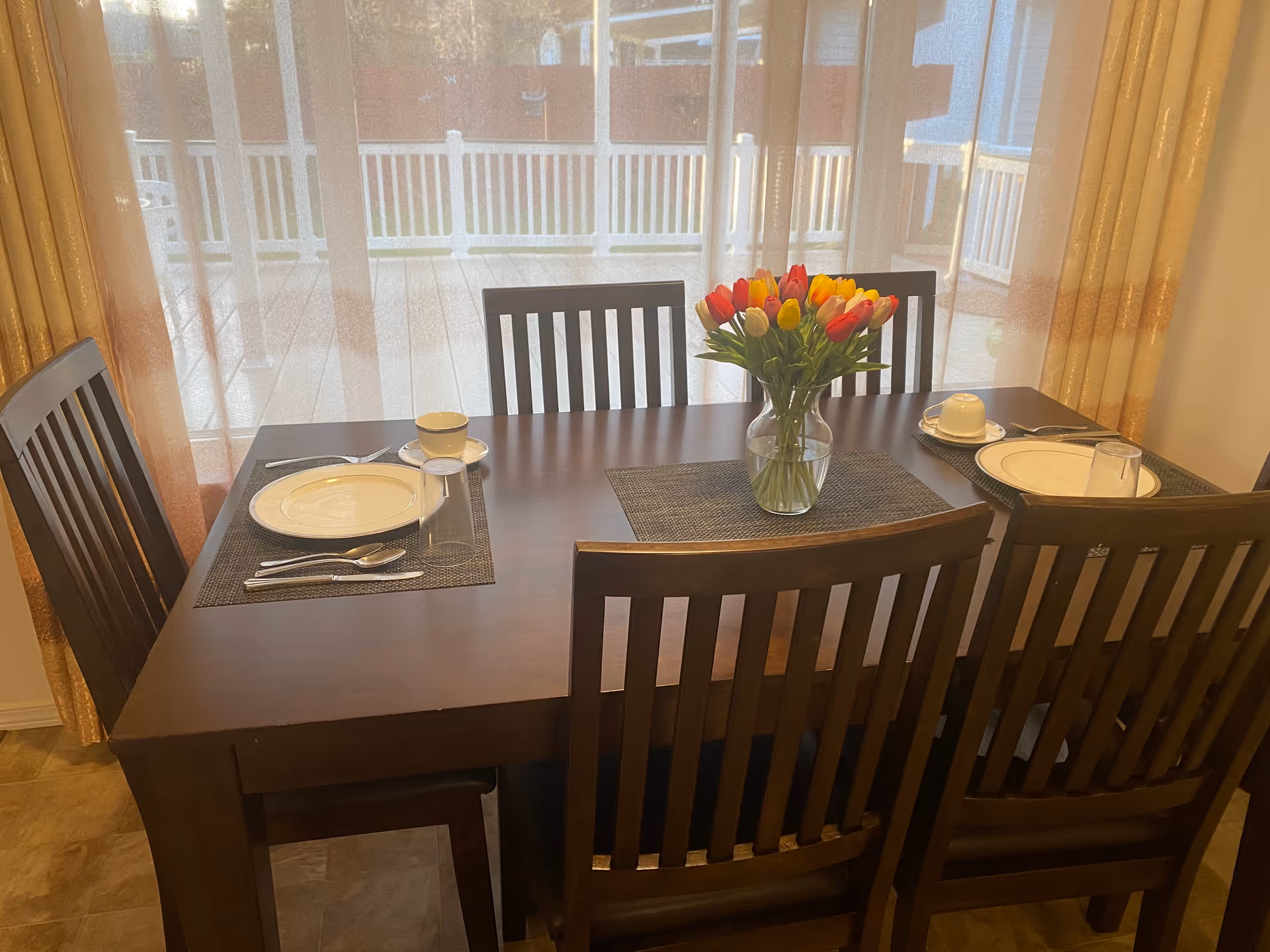 Dining table with place settings and a vase of tulips near the glass door
