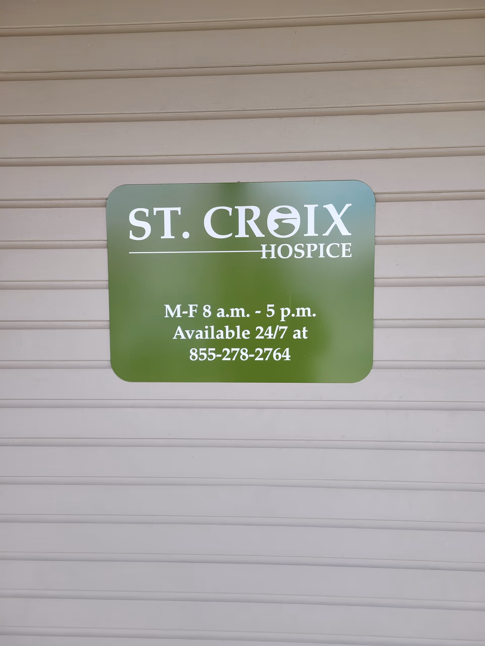Green St. Croix Hospice sign on a beige exterior wall.