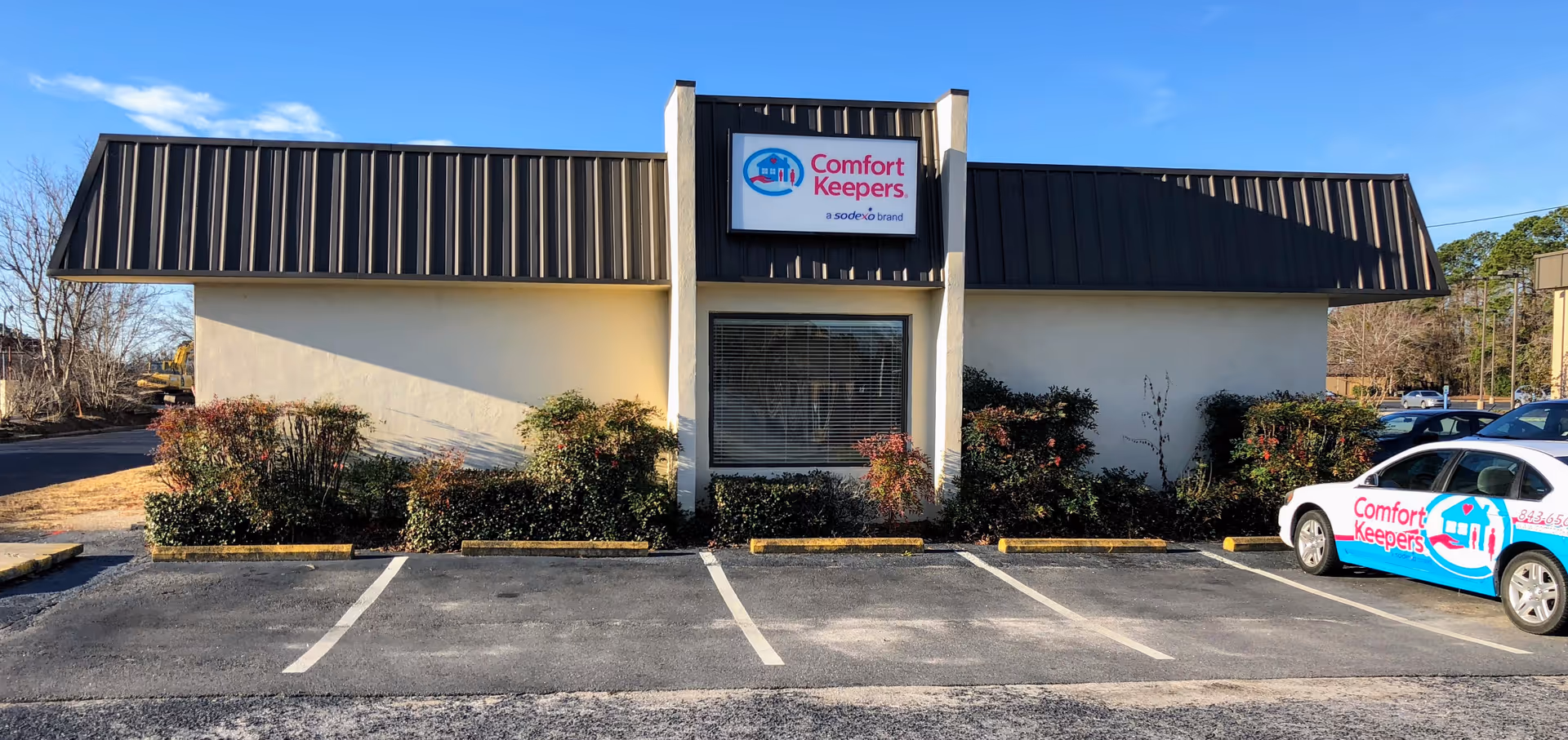 Front view of a Comfort Keepers Home Care building with a parked branded car.