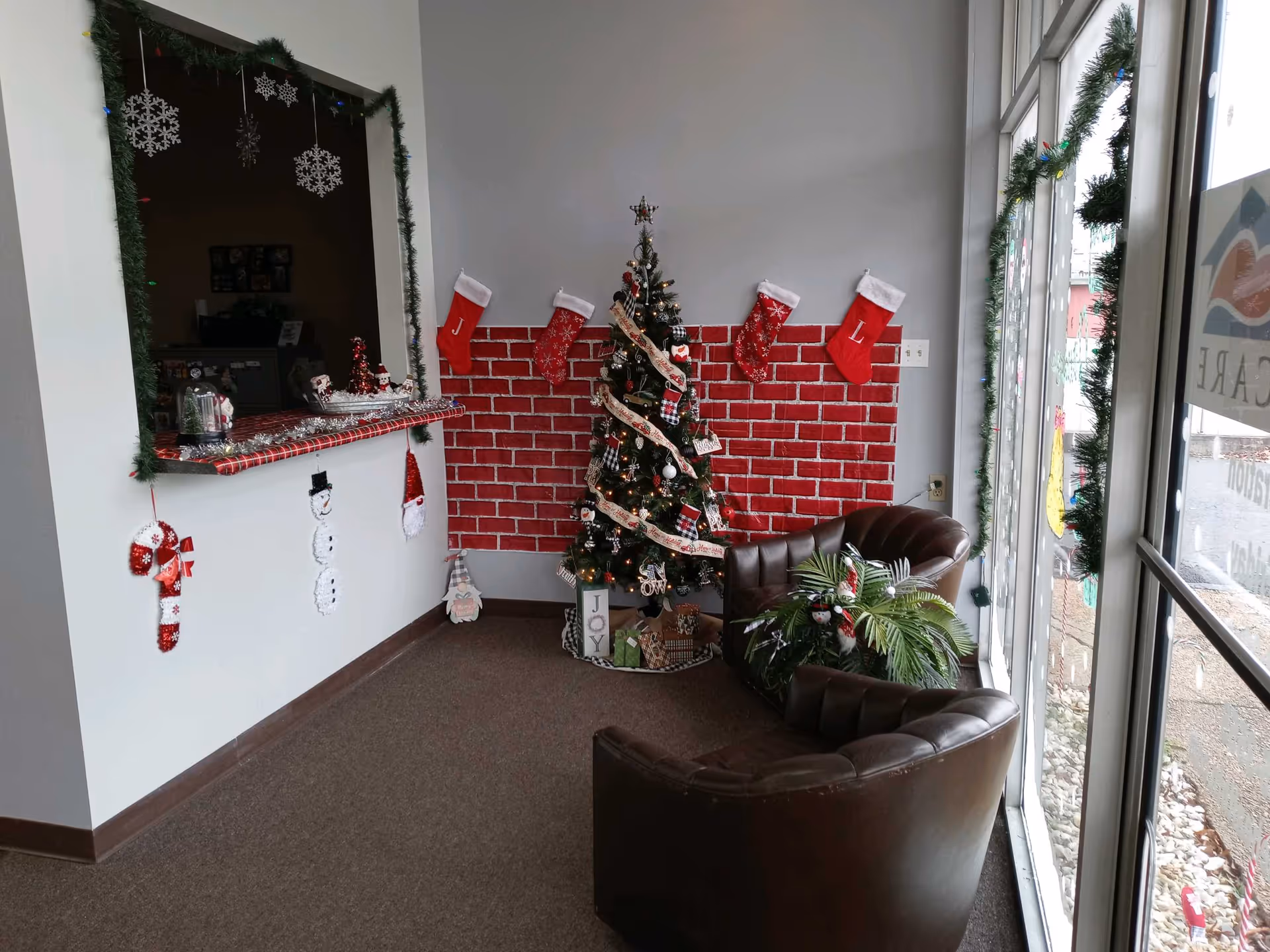 Cozy interior lounge area with Christmas tree, stockings, and festive decor near large windows.
