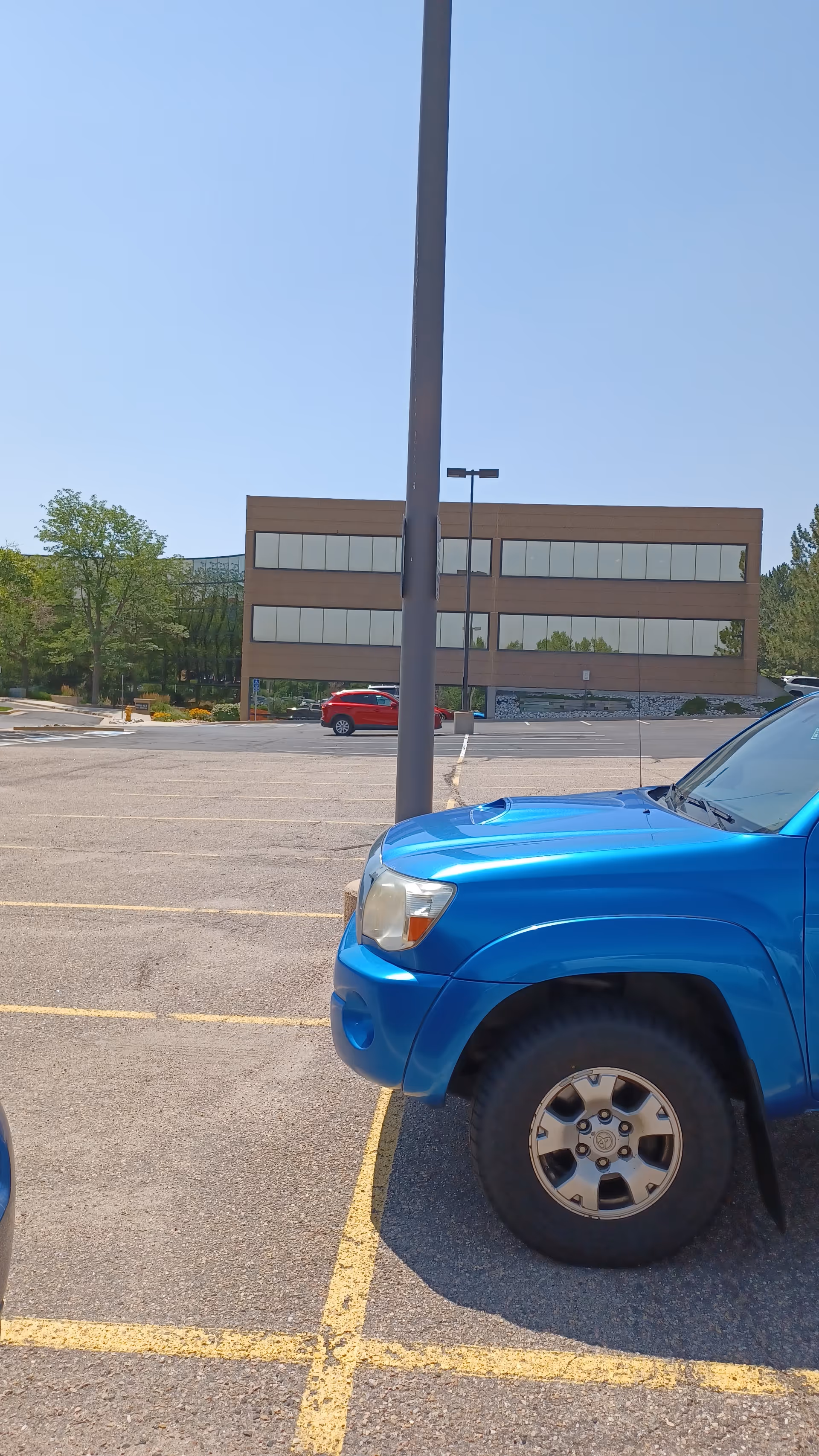Parking lot in front of a beige building with a blue pickup truck.