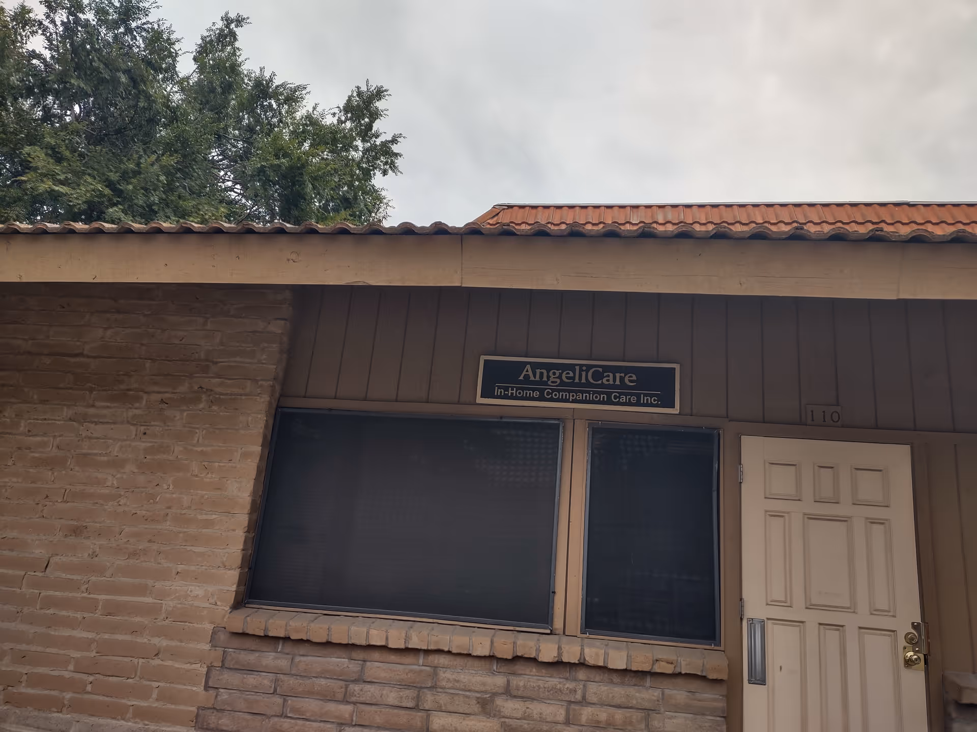 Front view of a brick building entrance with AngeliCare sign and a white door.
