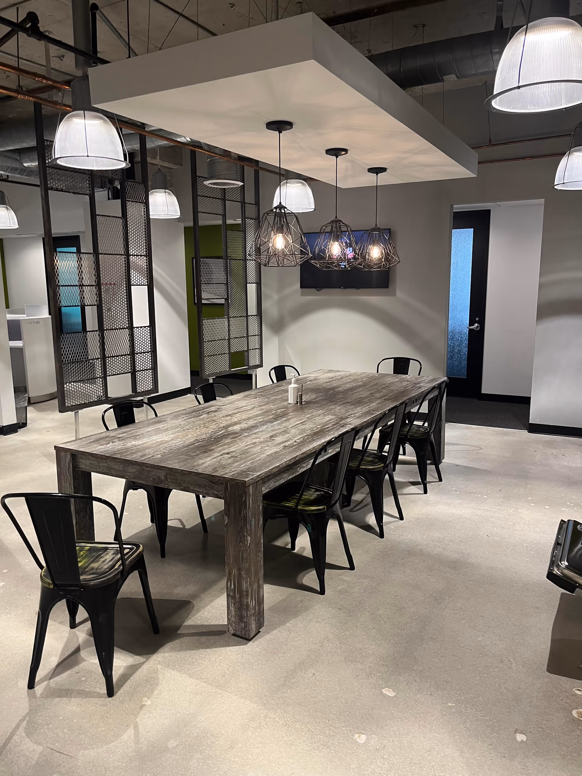 Industrial dining area with a long wooden table and metal chairs indoors.