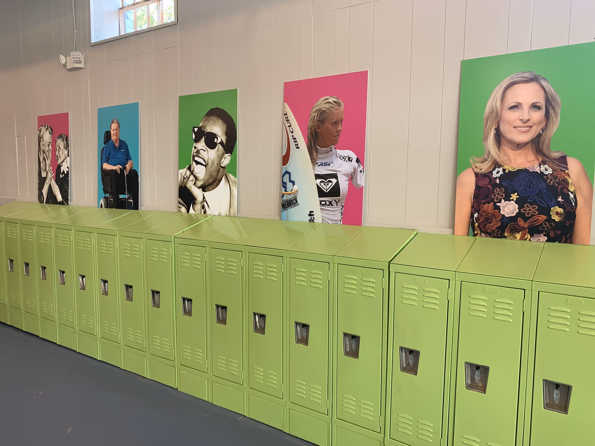 Interior hallway featuring lime-green lockers and large vibrant portraits on the wall.