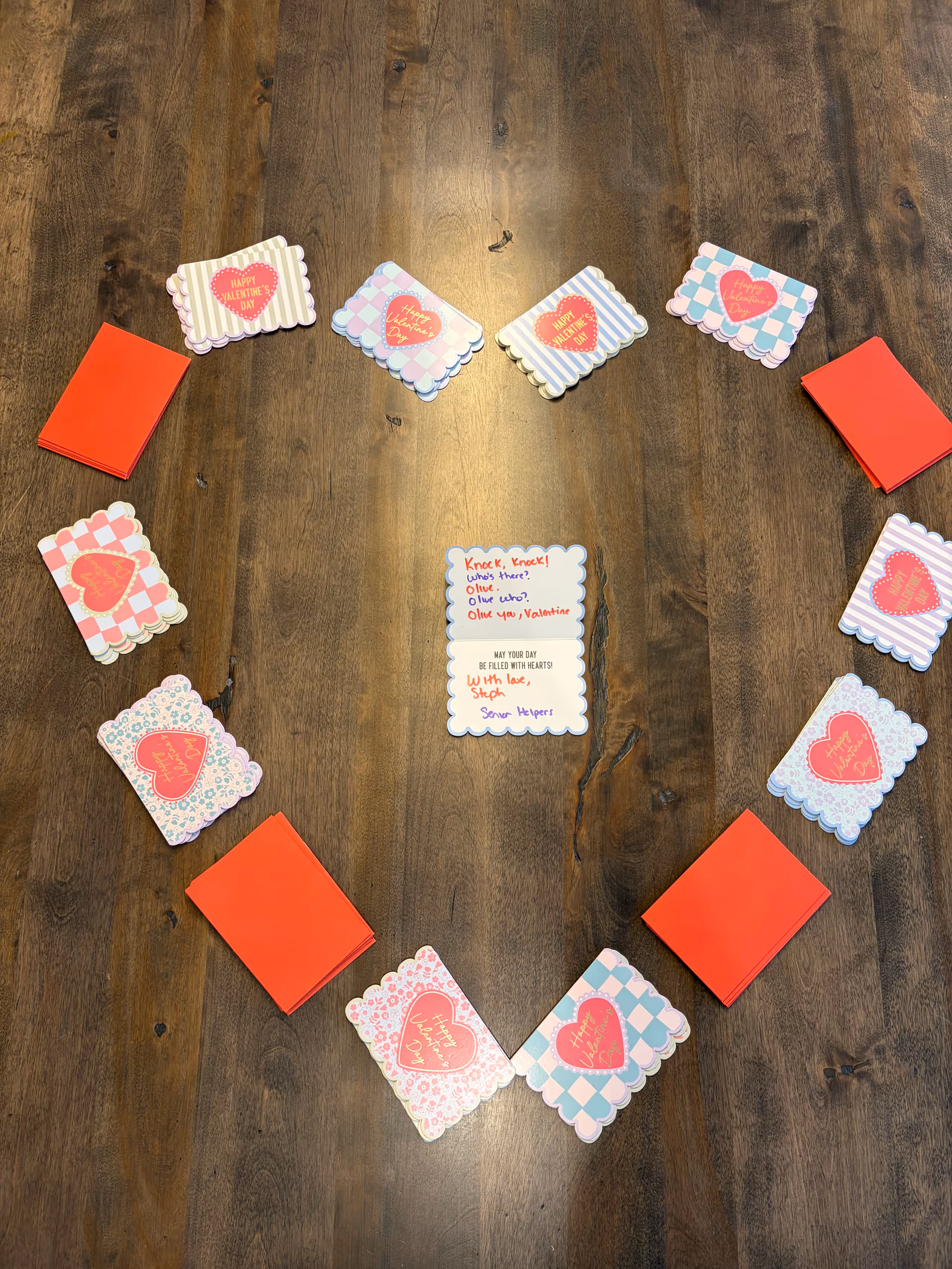Valentine cards arranged in a circle on a wooden floor with red envelopes