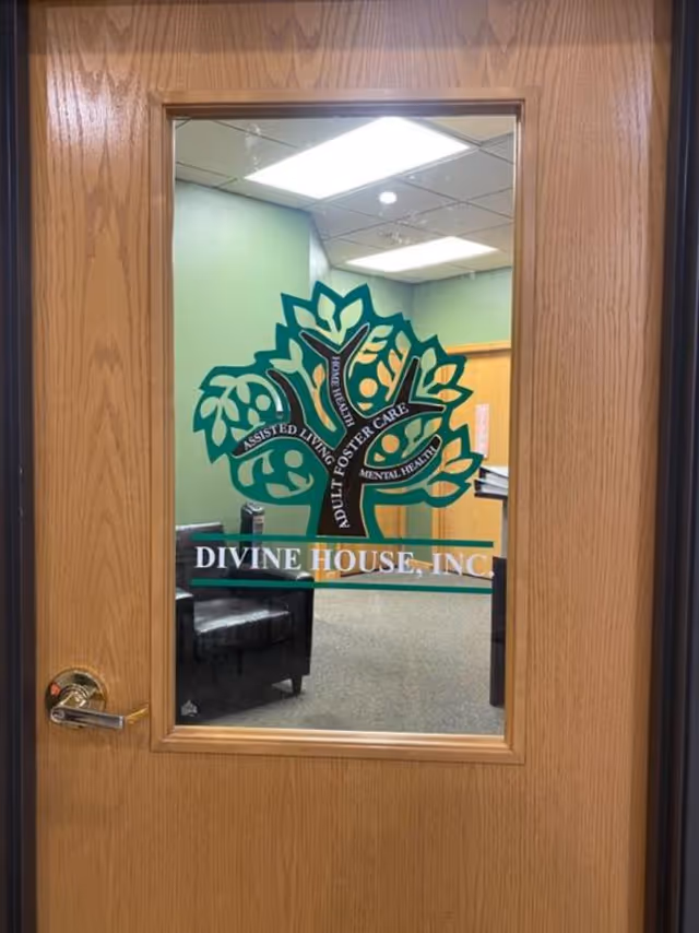 Wooden framed glass door features Divine House, Inc. logo with a green tree inside.