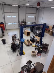 Interior workshop with a car lift, tools, and stacked boxes.