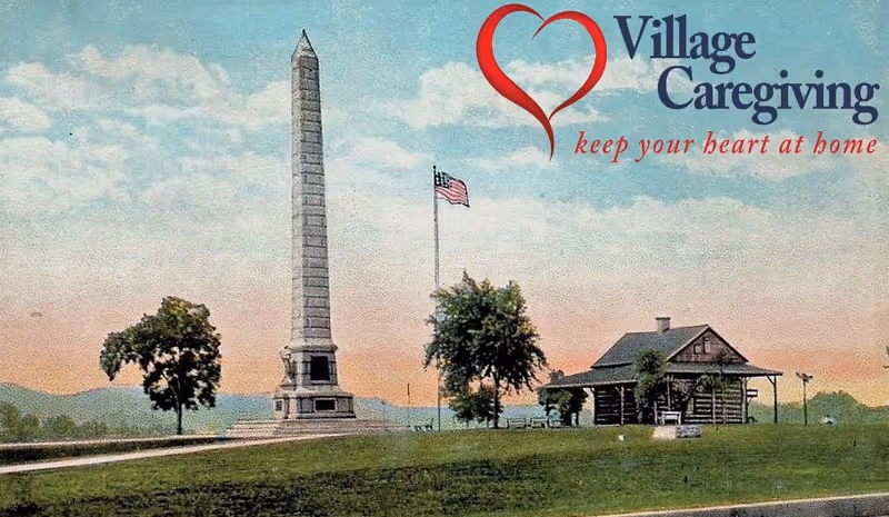Outdoor park scene with obelisk, flagpole, trees, and a small cabin, Village Caregiving logo.