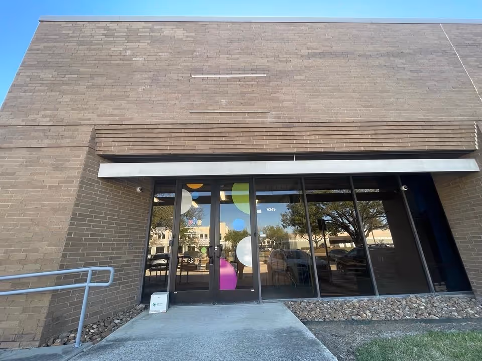 Brick building entrance with glass doors decorated by colorful circular shapes.