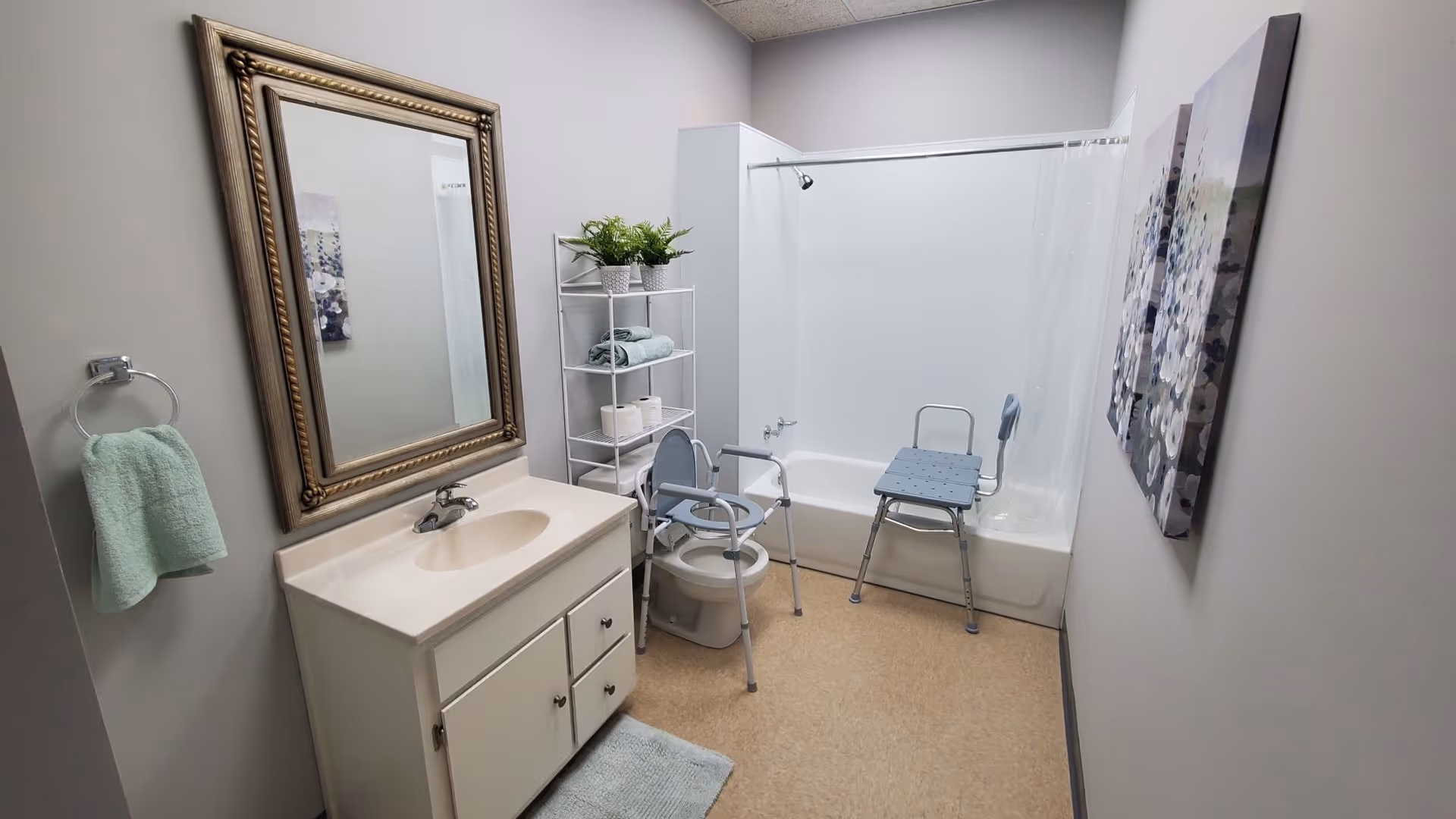 Accessible bathroom with sink, large mirror, shelves, a tub with shower, and a blue shower chair.
