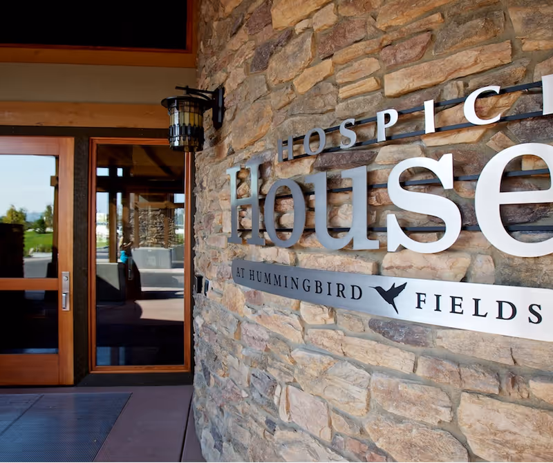 Stone building entrance with Hospice of North Idaho sign and glass doors