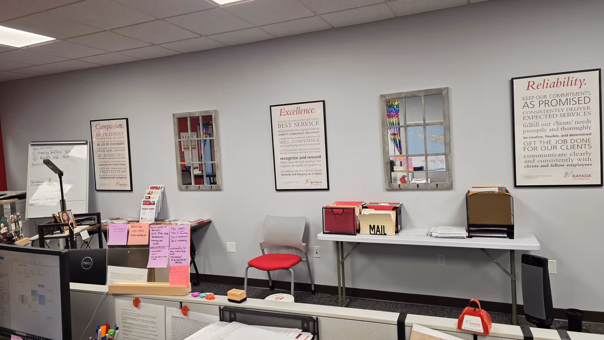 Office reception area with desks, computers, and wall posters inside a BAYADA facility.