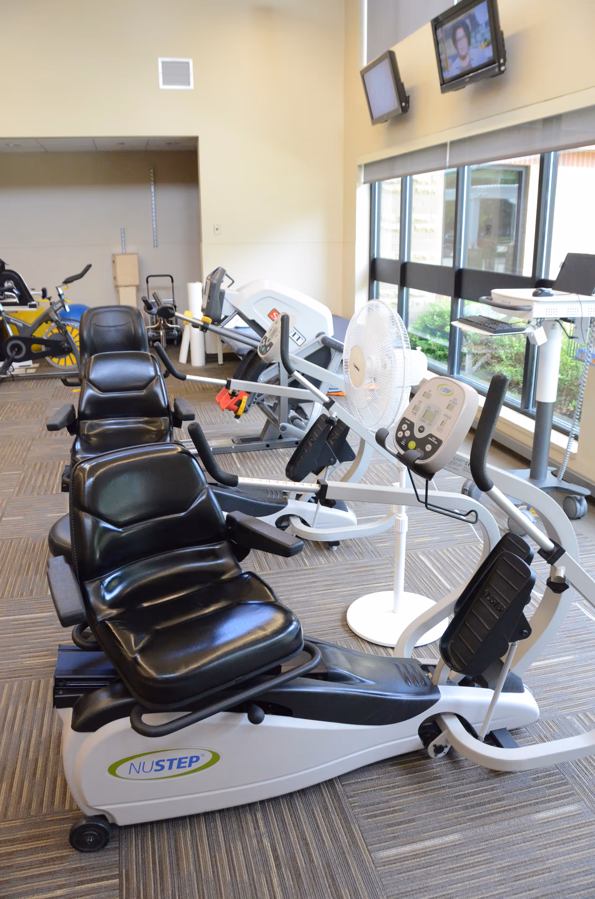 Indoor fitness room with NuStep machines and a large window.