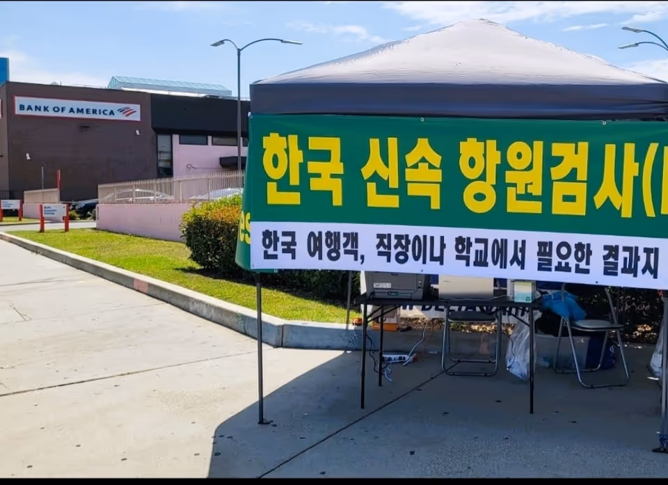 Outdoor tent with large green Korean banner beside a Bank of America building
