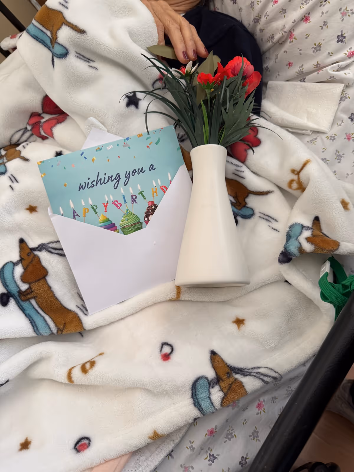 Resident in a bed with a birthday card and flowers.