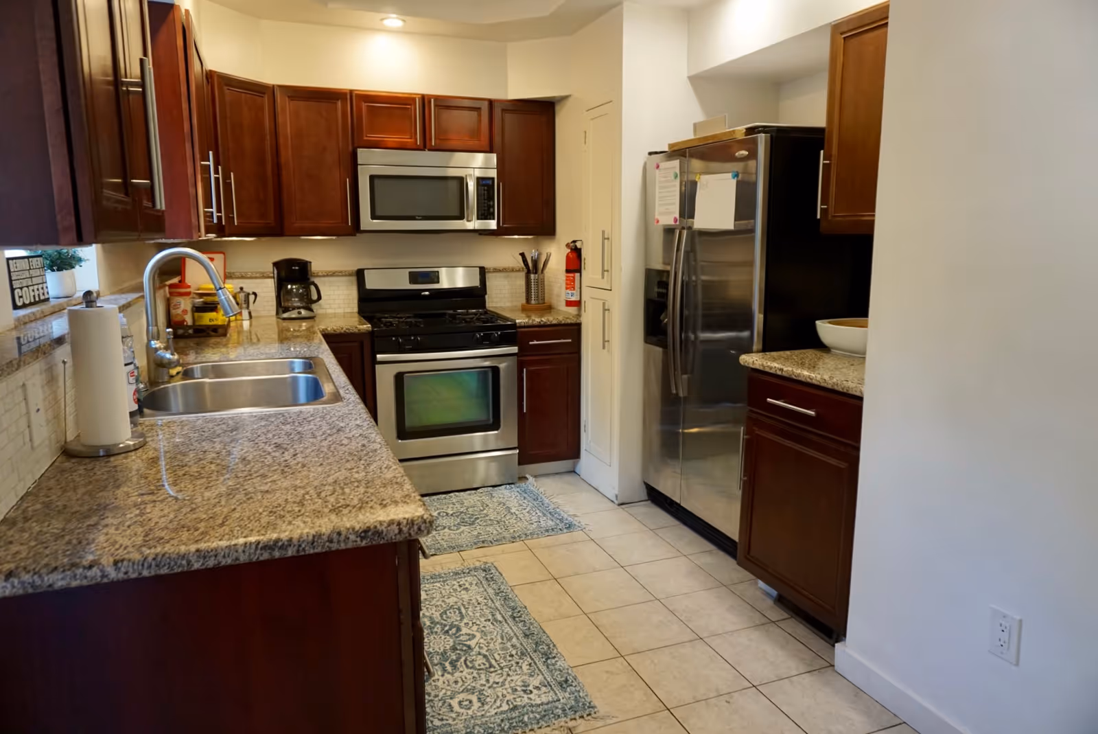 Modern kitchen with granite counters, dark wood cabinets, stainless steel appliances, and a double sink.