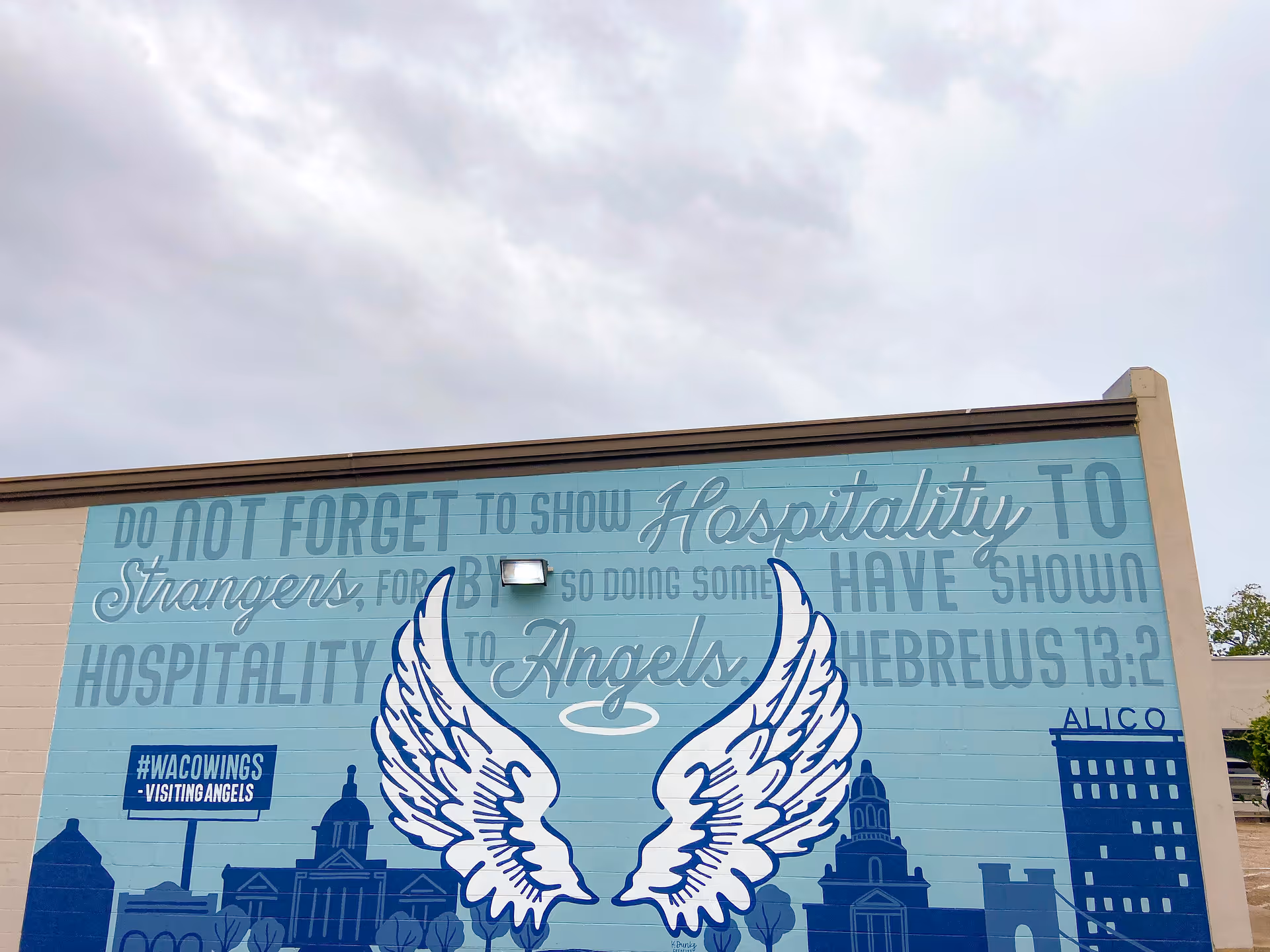 Exterior wall mural at Visiting Angels Senior Home Care, featuring angel wings and scripture.