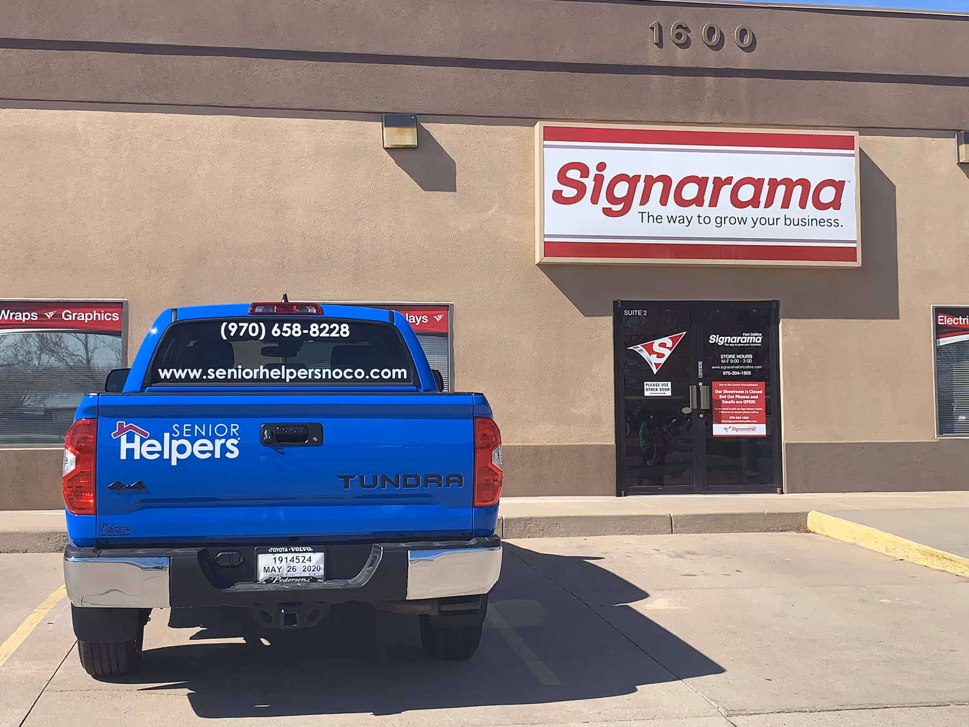 Bright blue Senior Helpers truck parked in front of a Signarama storefront.