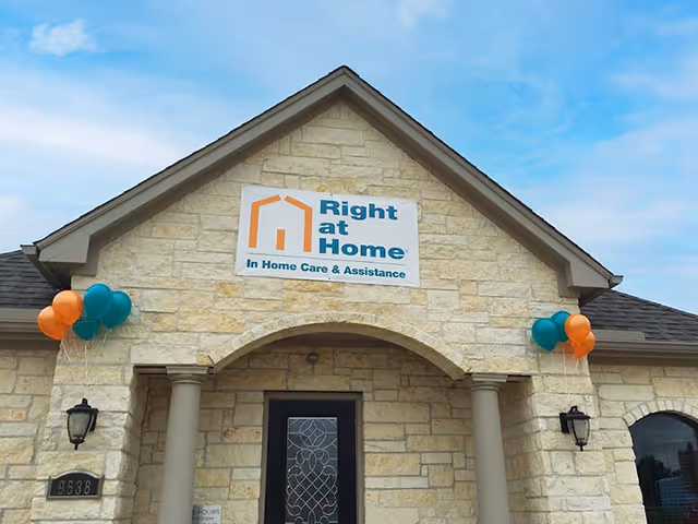 Stone-faced building entrance with Right at Home sign and balloons.
