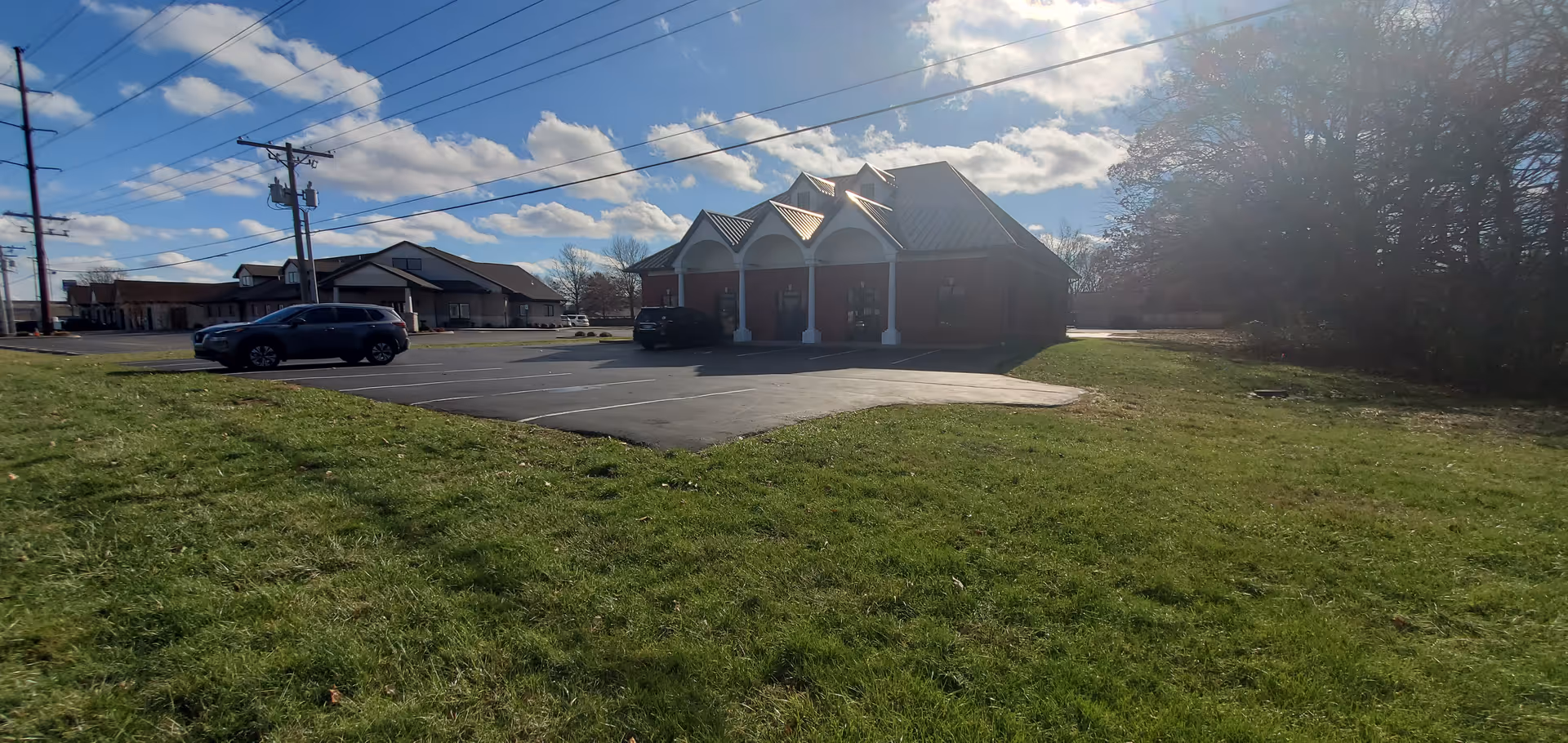 Exterior view of a brick hospice building with a driveway and grassy lawn.