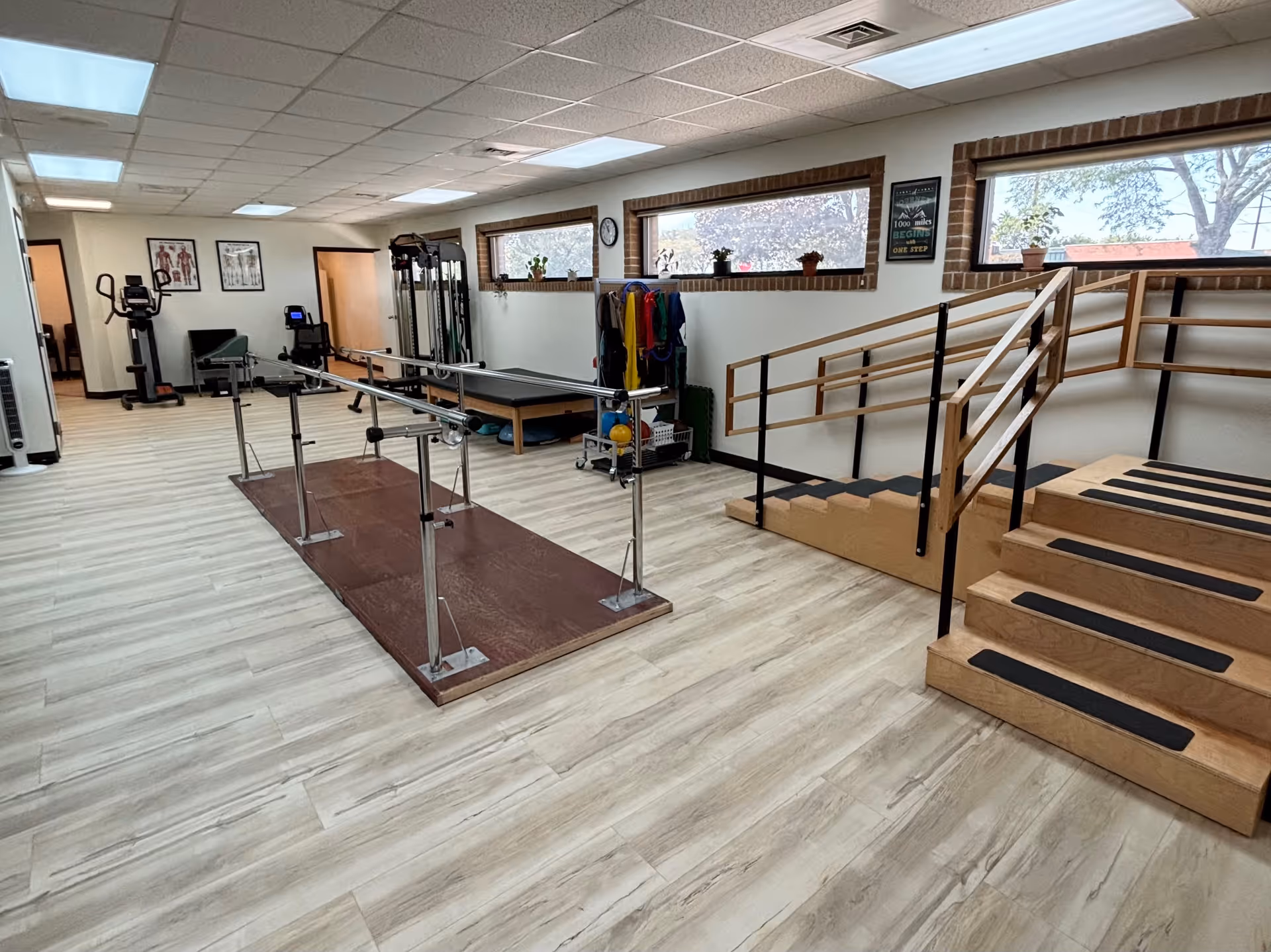 Rehabilitation gym with parallel bars, treadmills, stairs, and other fitness equipment.