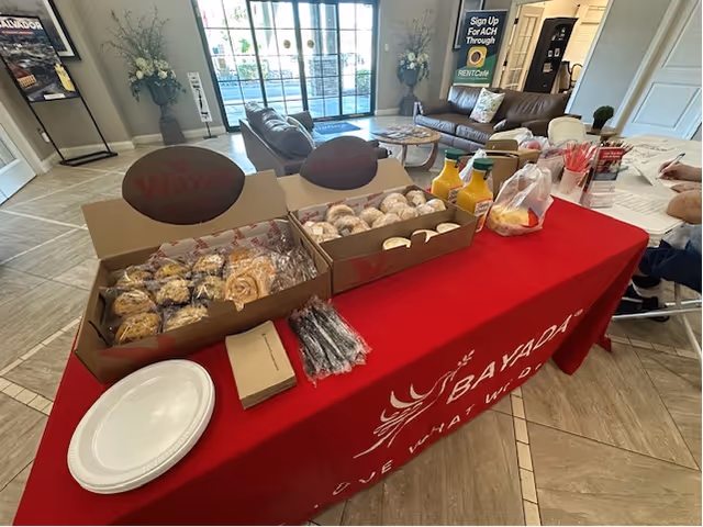 Lobby interior with a long red BAYADA table displaying snacks, drinks, and utensils.
