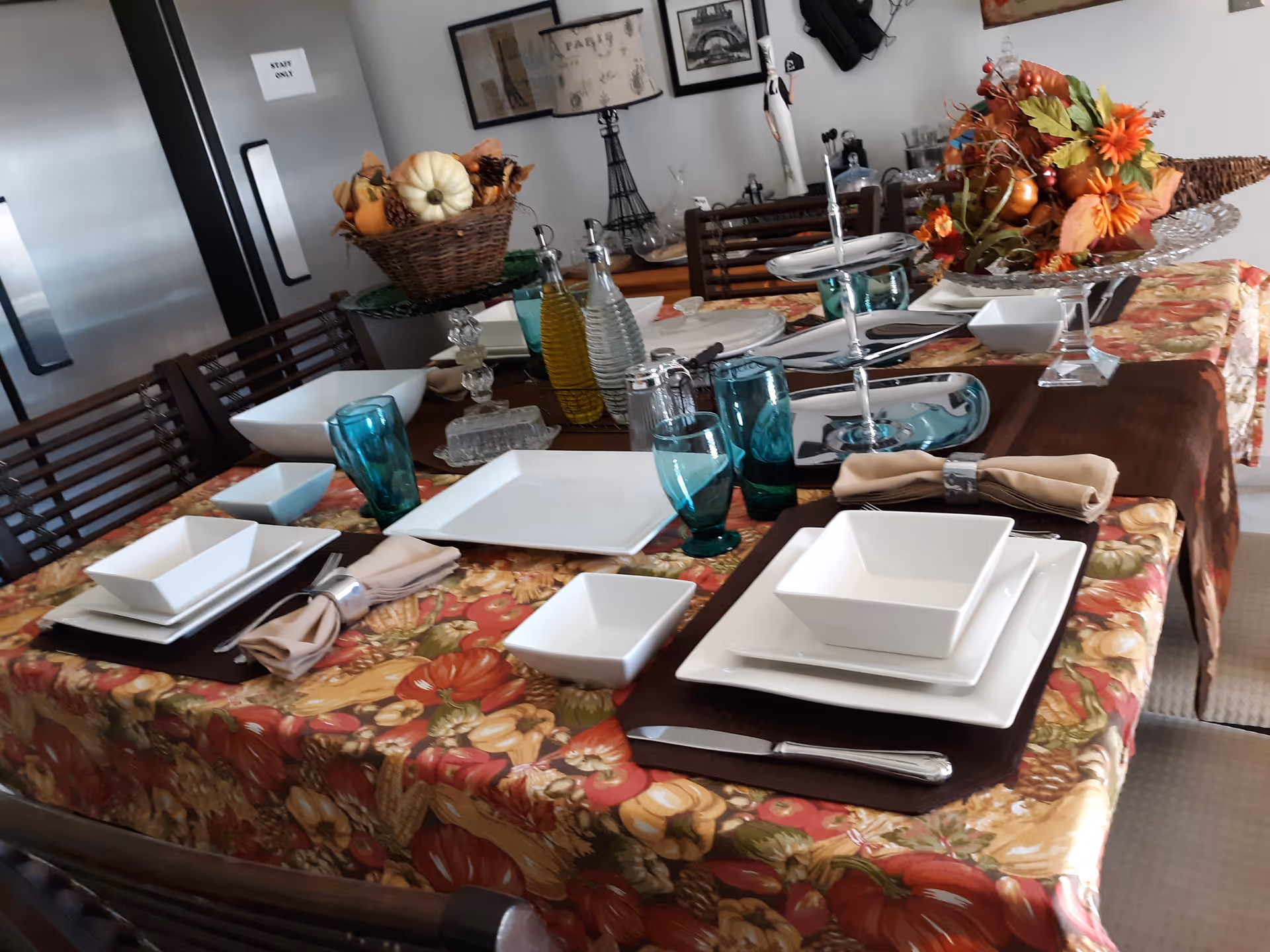 Fall-themed dining table set with dishes and centerpiece in a bright dining room.