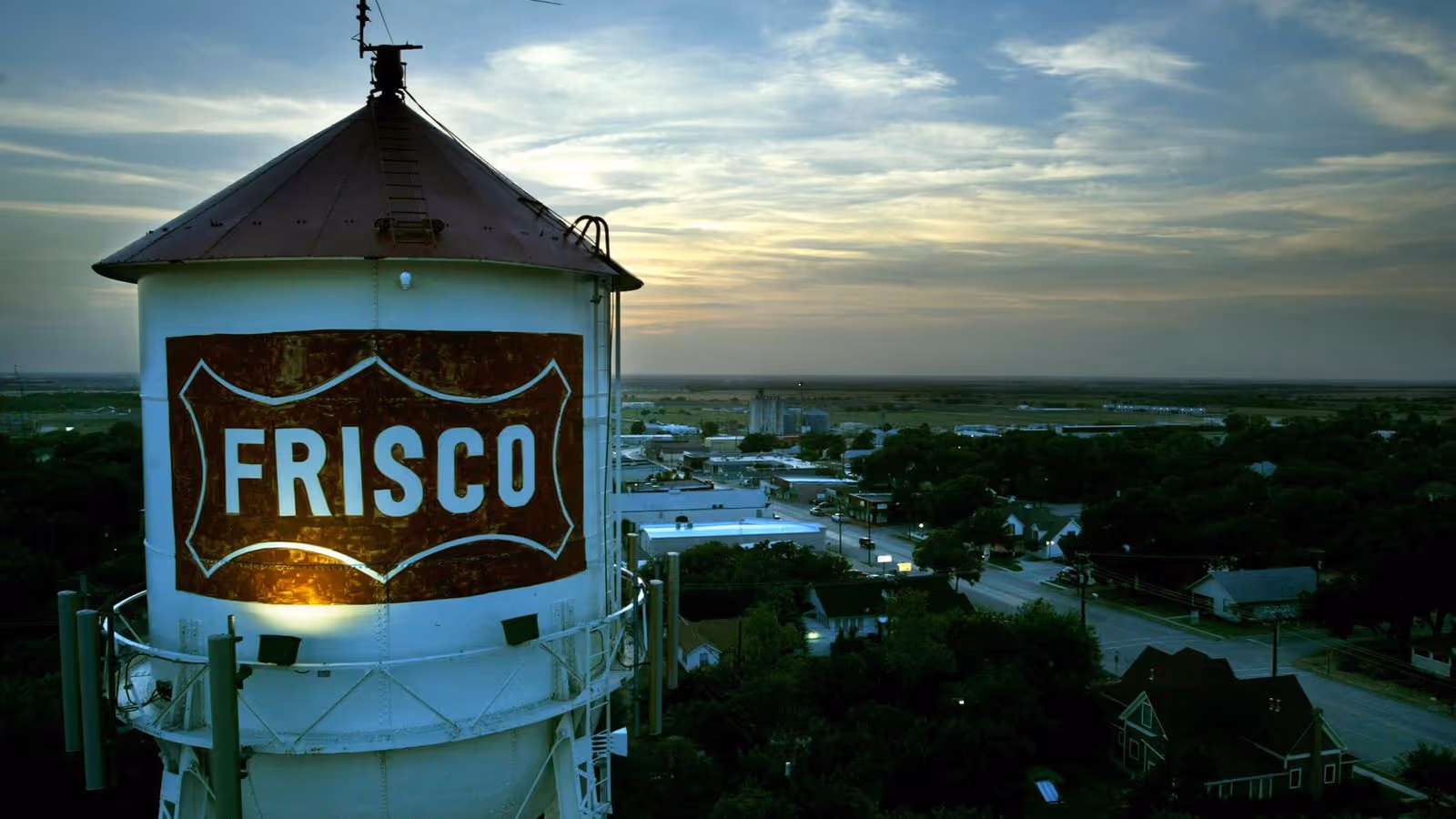 Aerial view of a Frisco water tower overlooking a small town at sunset
