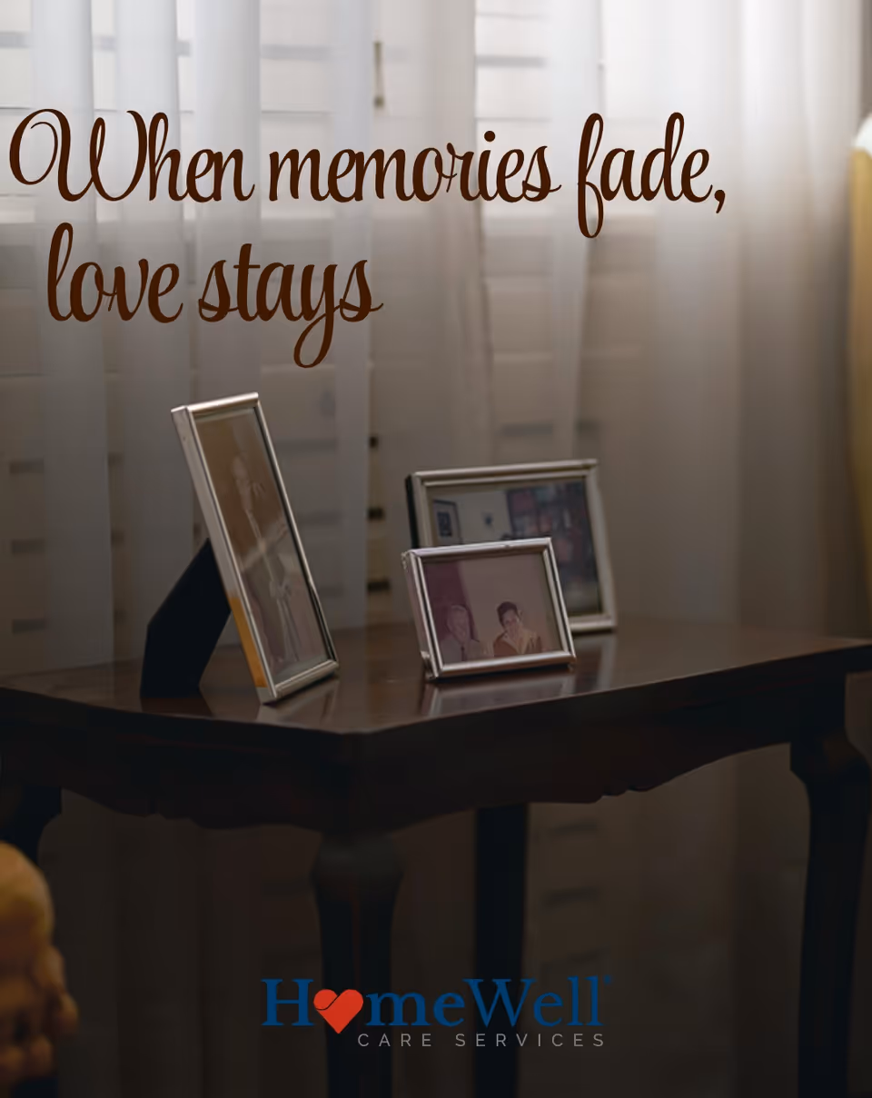 A wooden table holds framed photos beneath a cursive quote in a softly lit interior.