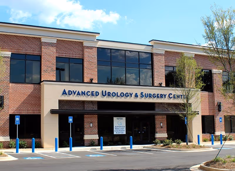 Brick medical clinic with large windows and blue sign reading Advanced Urology & Surgery Center.